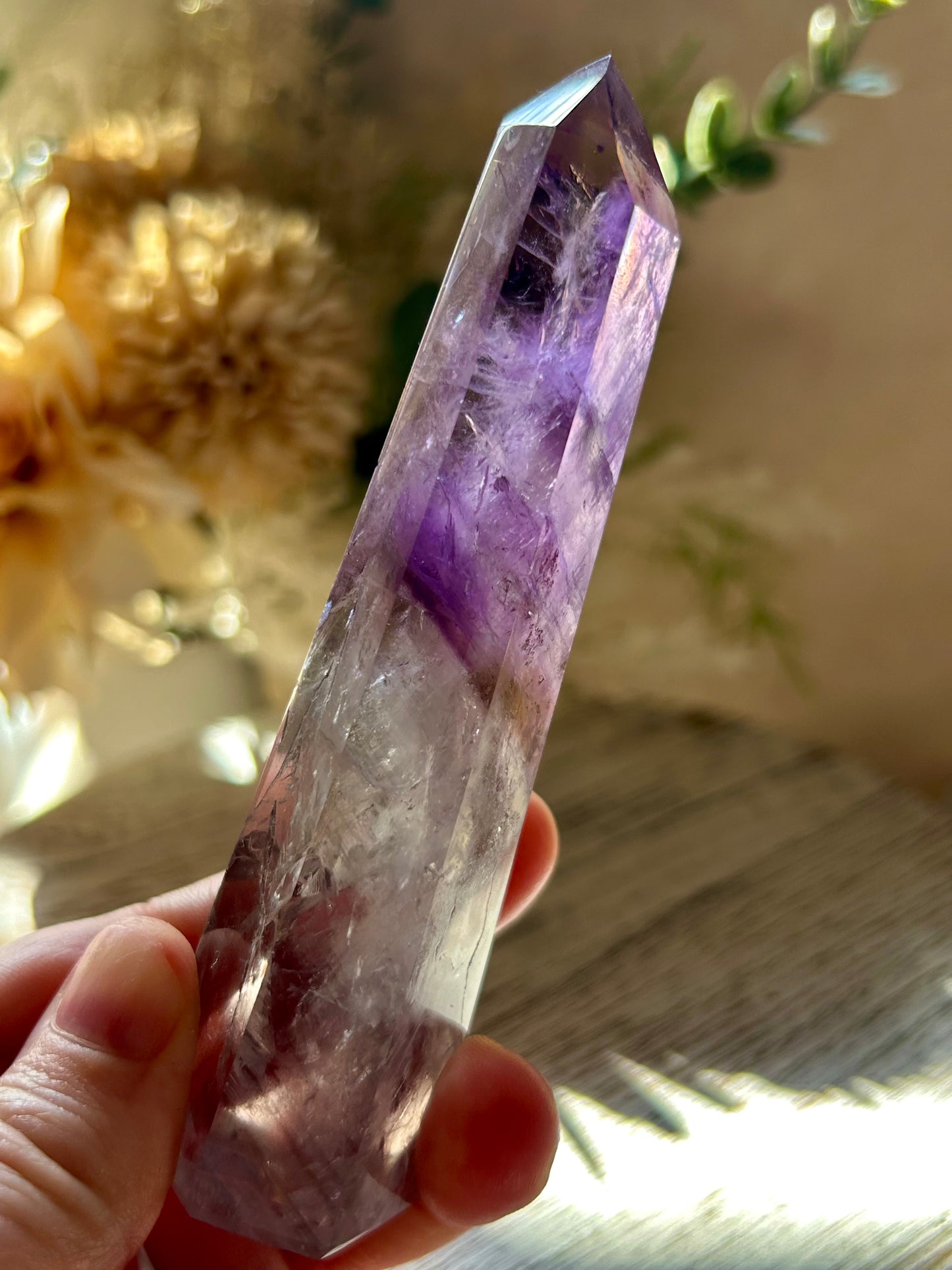 Amethyst crystal held in hand with natural background