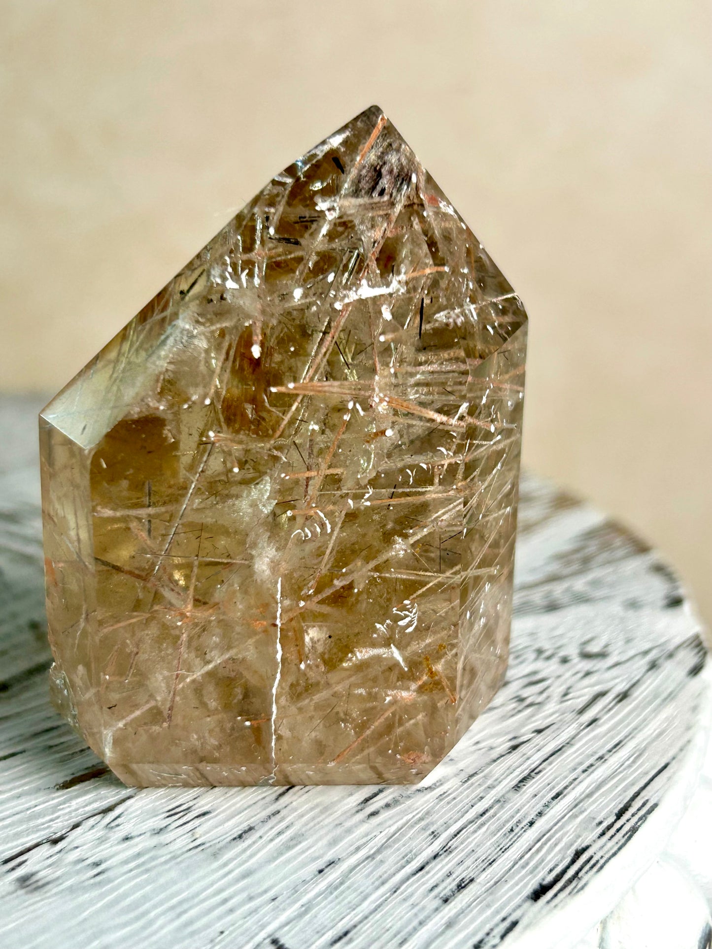 Citrine Rutile tower with golden threads on cream background and rustic wood surface