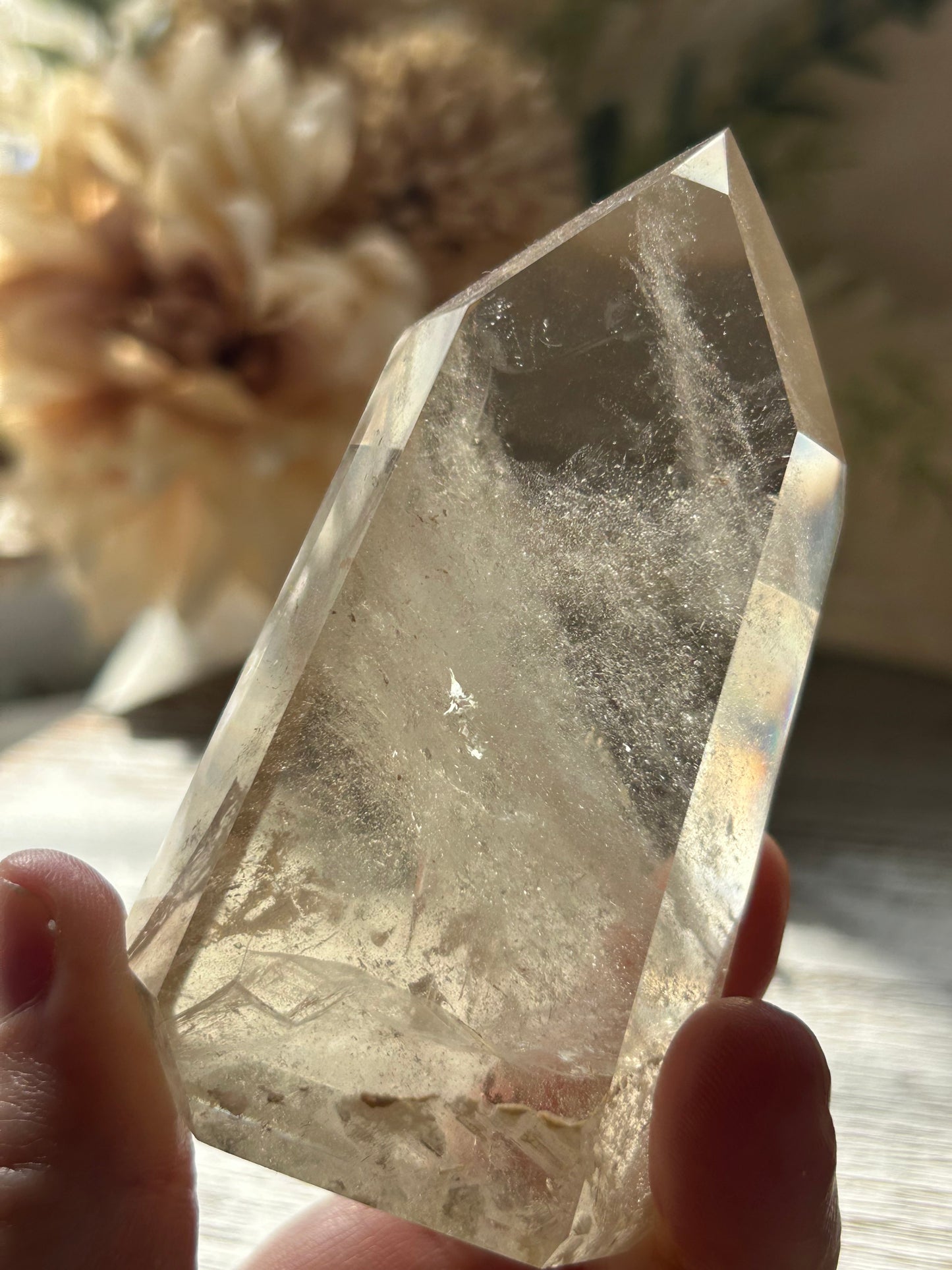 Clear crystal held by a hand with a blurred natural background