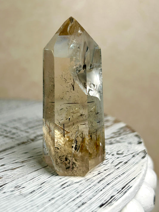 Citrine Rutile tower with golden threads on cream background and rustic wood surface