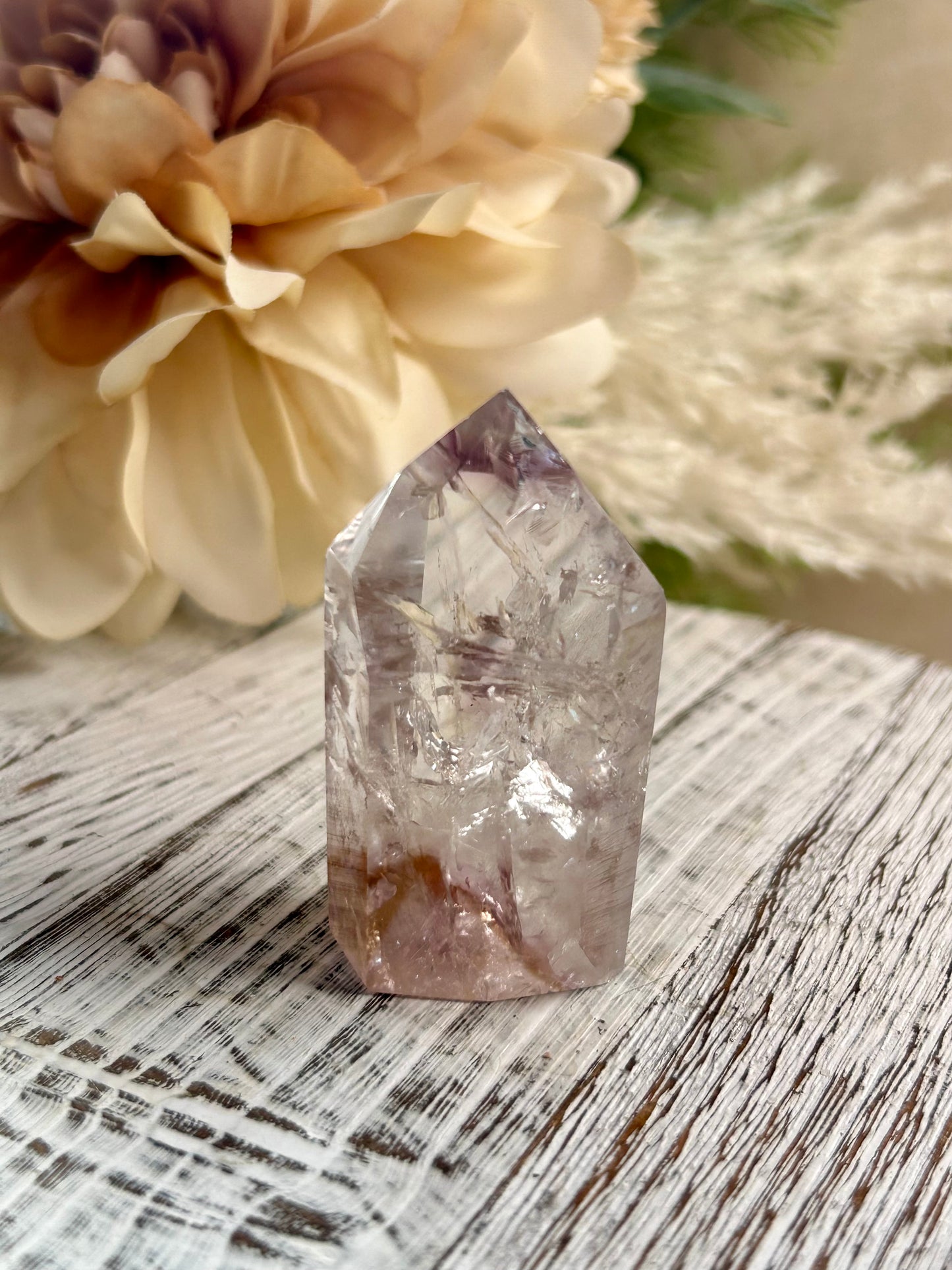 Crystal on a wooden surface with flowers in the background