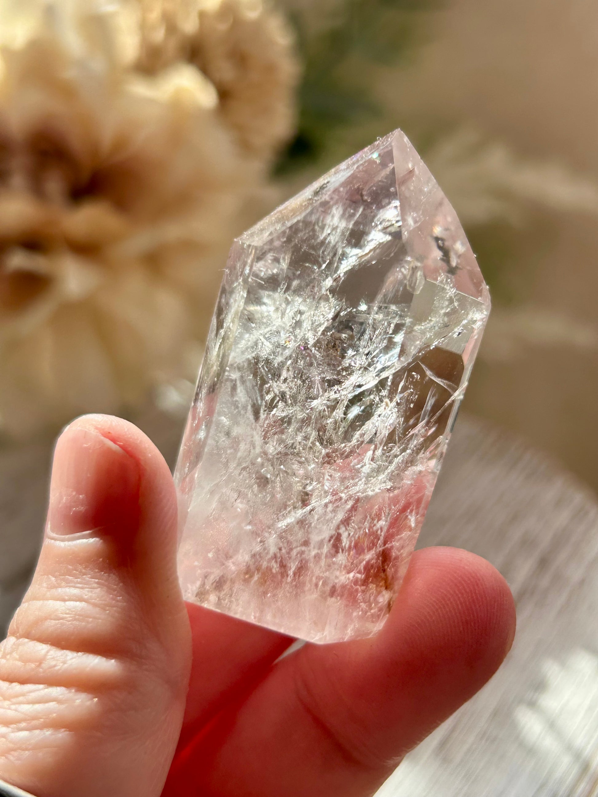 Clear crystal held in a hand with a blurred natural background
