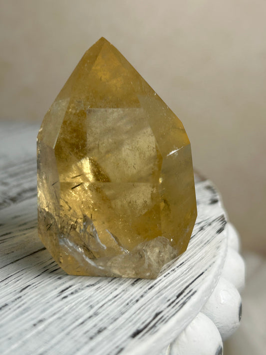 Citrine Rutile tower with golden threads on cream background and rustic wood surface