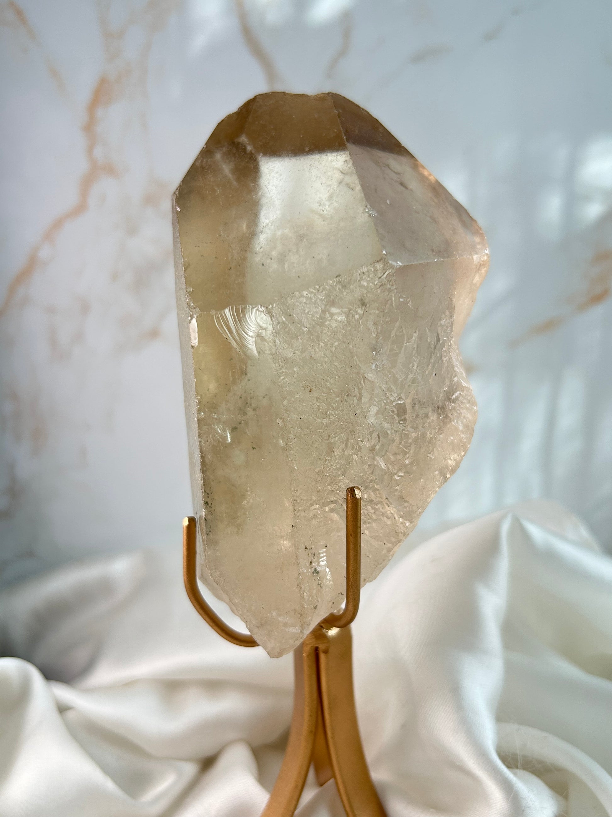 Large natural Citrine point from Brazil with golden hue on white satin background