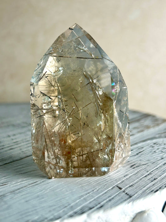 Citrine Rutile tower with golden threads on cream background and rustic wood surface