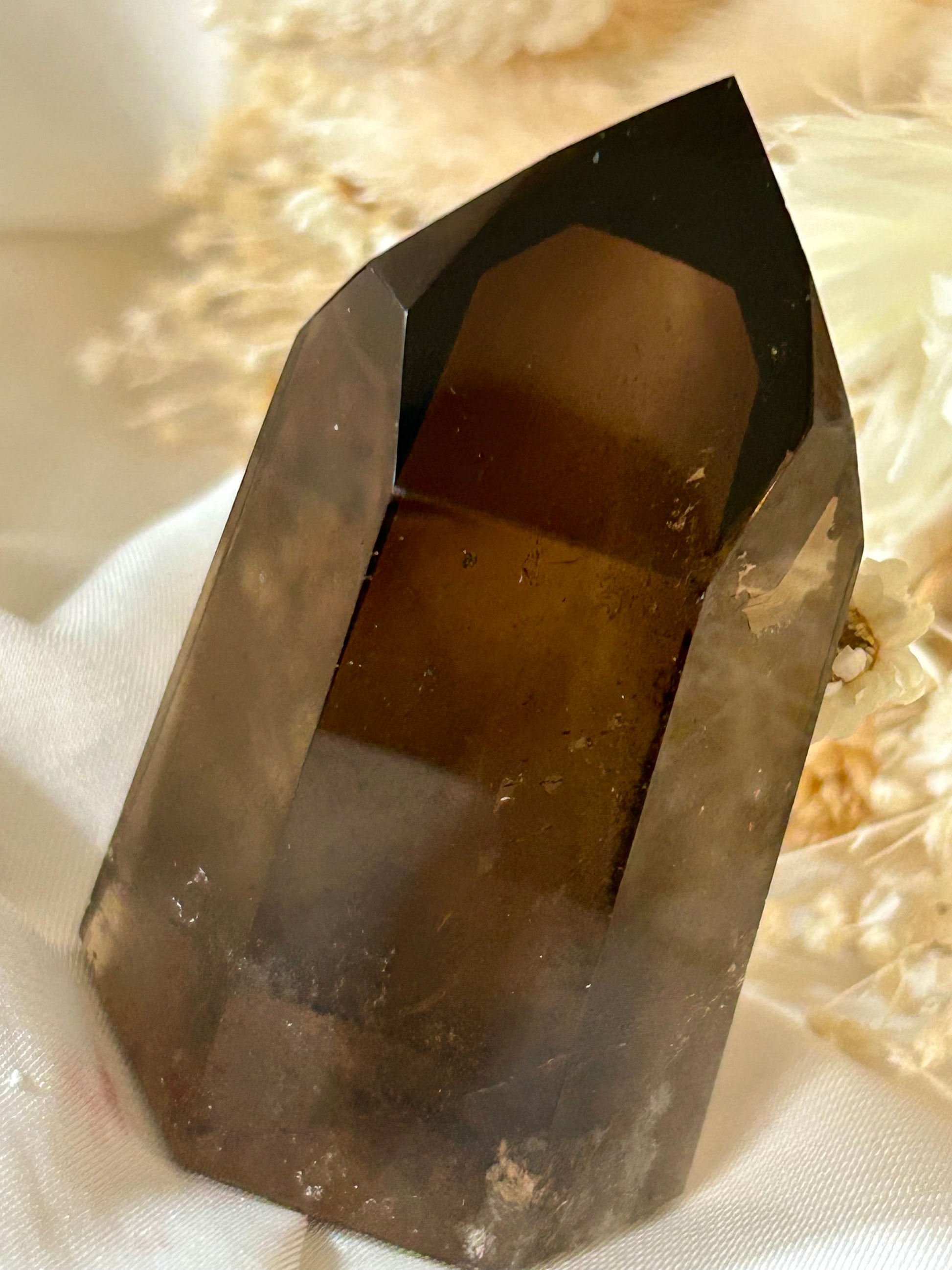 Smokey Quartz crystal with warm brown tones and soft clarity, standing upright on neutral background