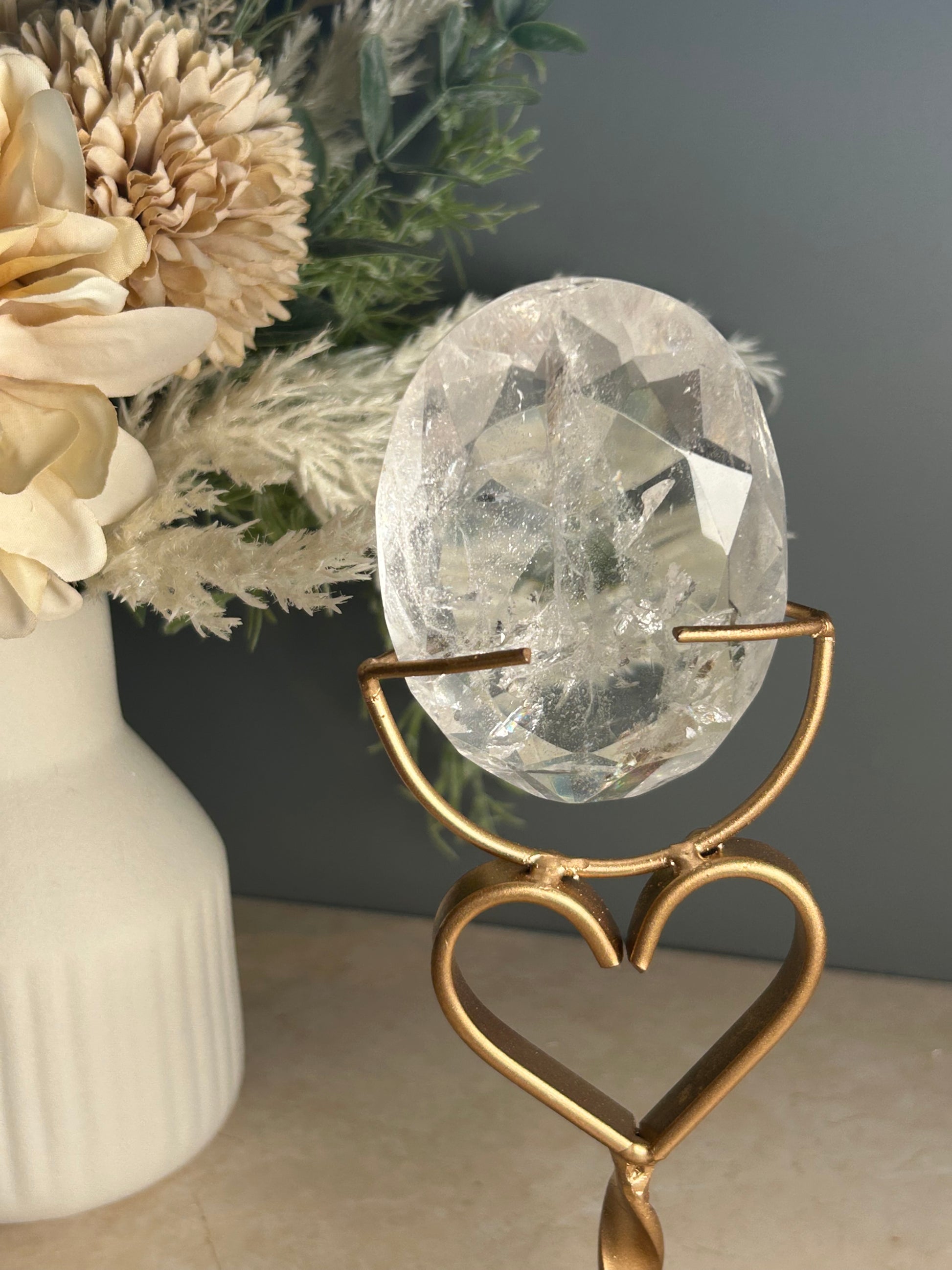 Faceted clear quartz crystal display piece on gold stand with geometric cut natural quartz specimen.