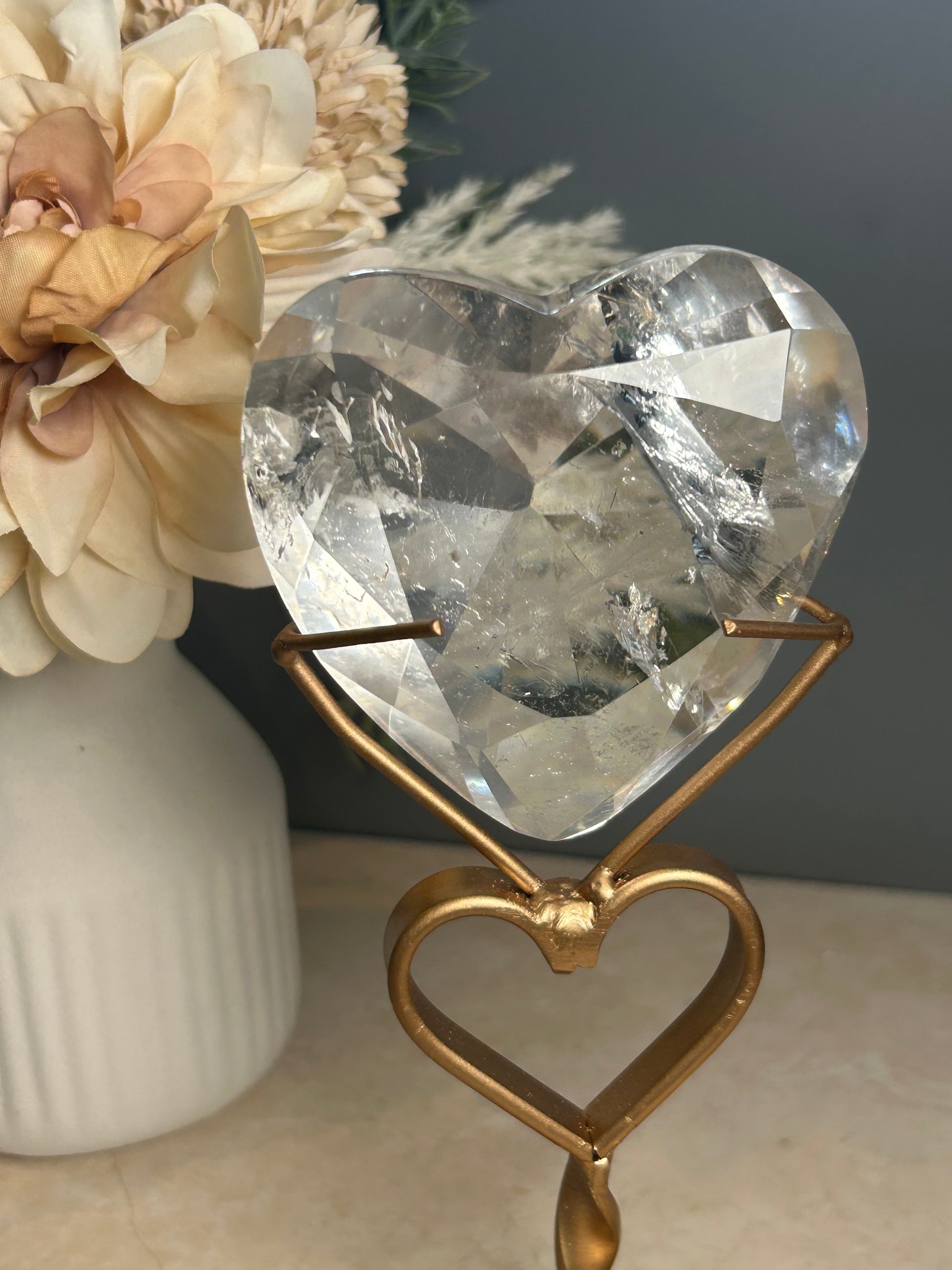 Faceted clear quartz crystal display piece on gold stand with geometric cut natural quartz specimen.
