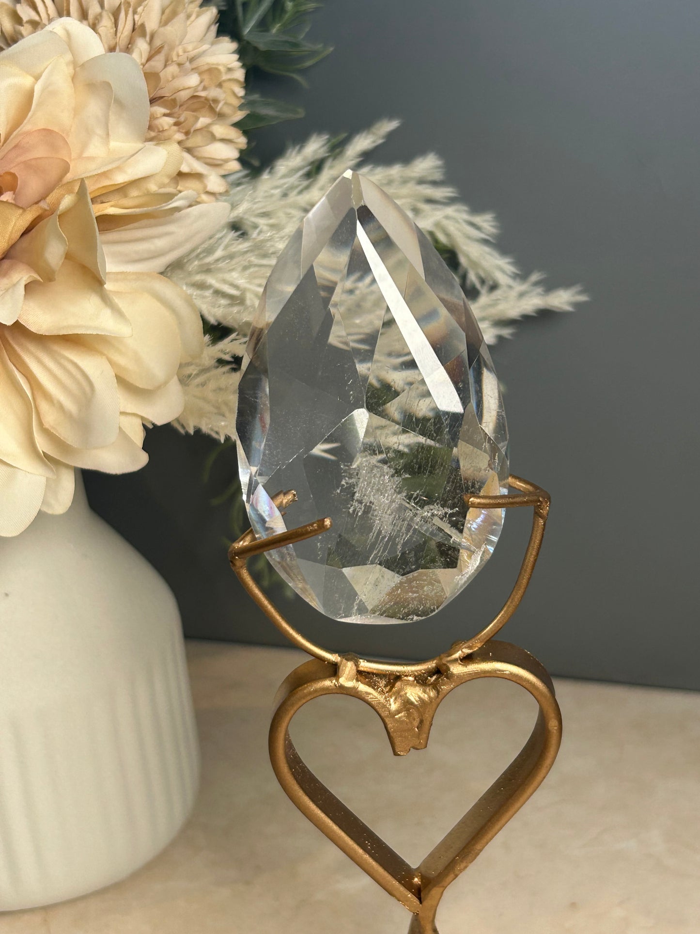 Faceted clear quartz crystal display piece on gold stand with geometric cut natural quartz specimen.
