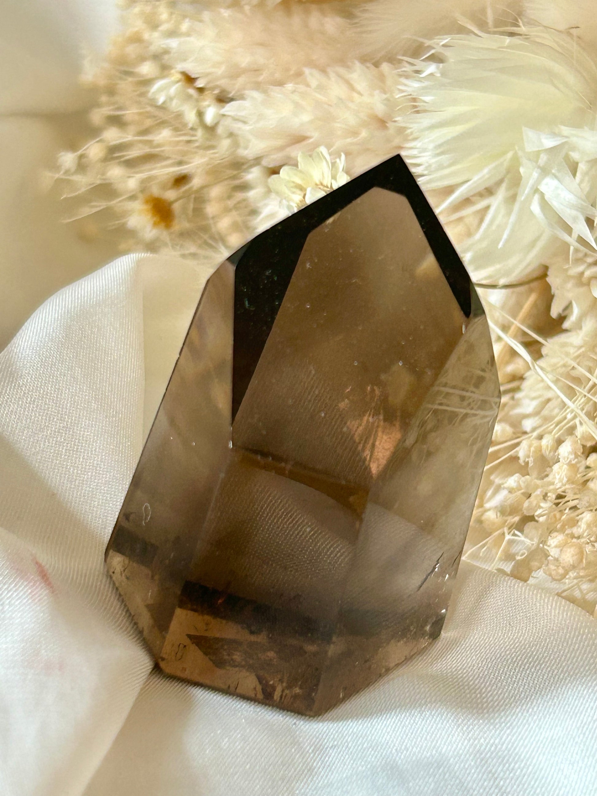 Smokey Quartz crystal with warm brown tones and soft clarity, standing upright on neutral background
