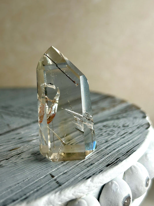Citrine Rutile tower with golden threads on cream background and rustic wood surface