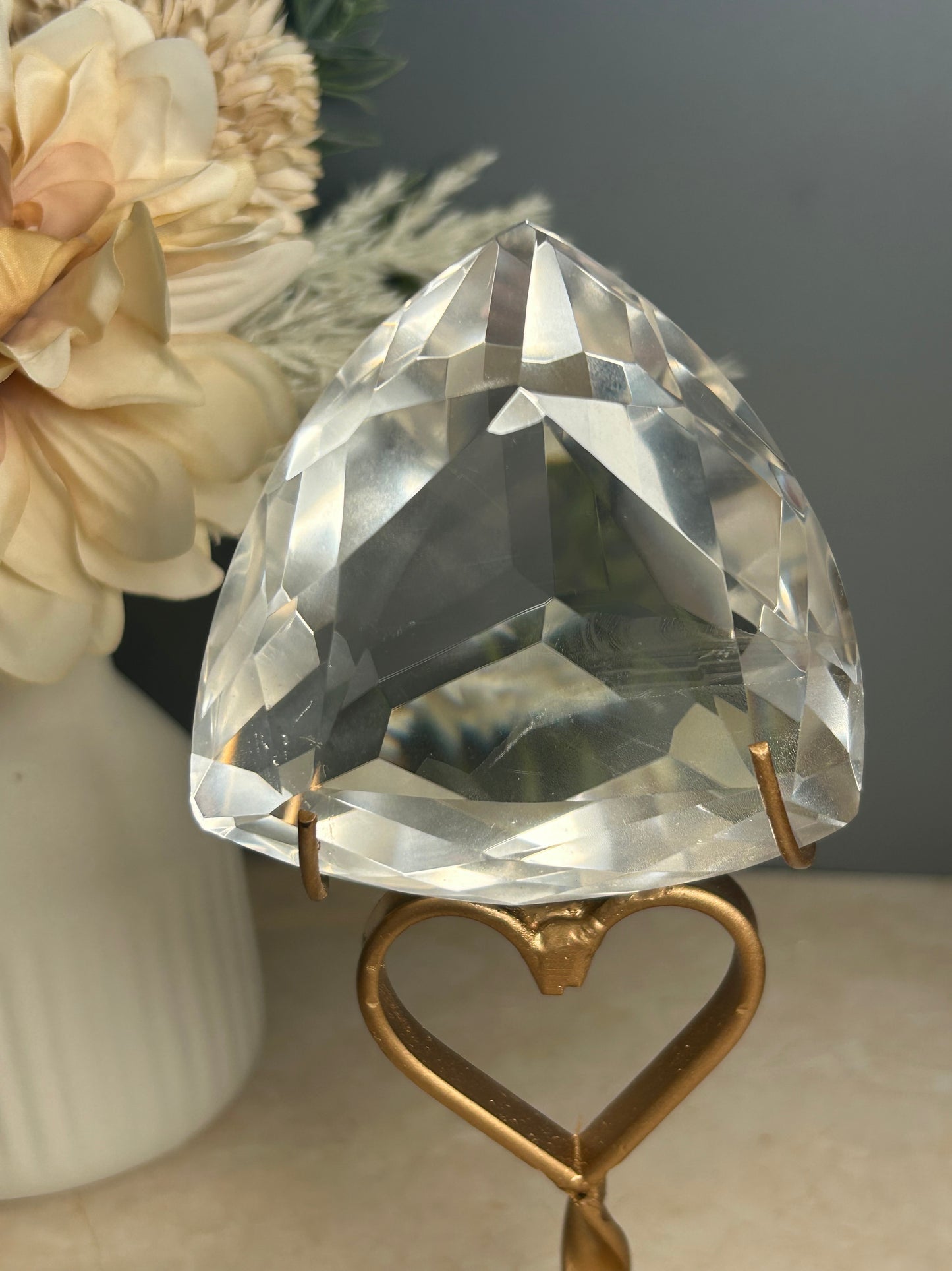 Faceted clear quartz crystal display piece on gold stand with geometric cut natural quartz specimen.

