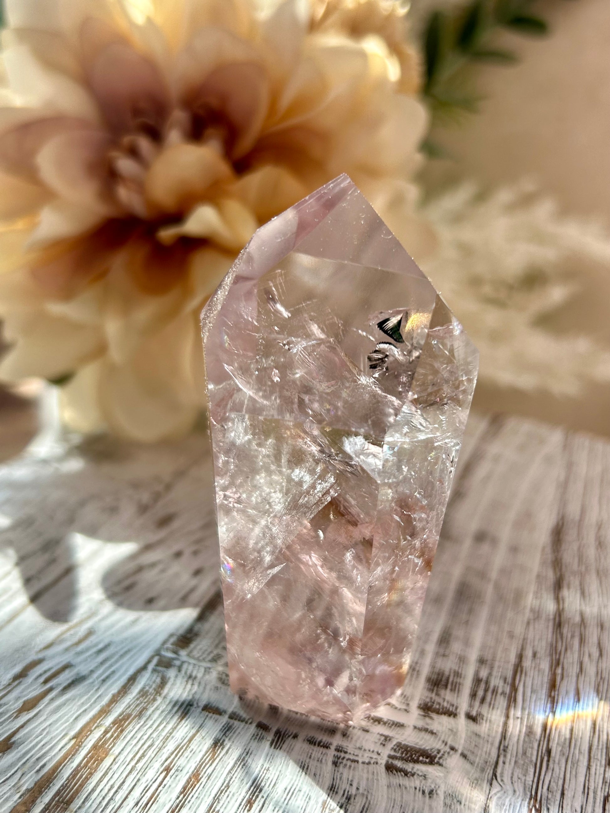 Clear crystal on a wooden surface with flowers in the background