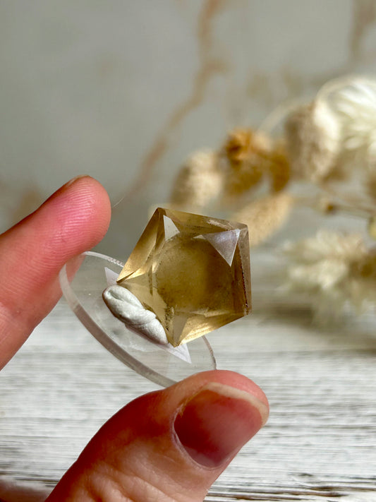 Faceted natural Citrine freeform with soft golden colour and visible internal inclusions, displayed against a neutral background.