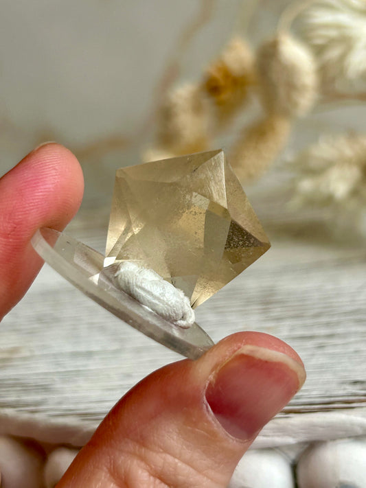 Faceted natural Citrine freeform with soft golden colour and visible internal inclusions, displayed against a neutral background.