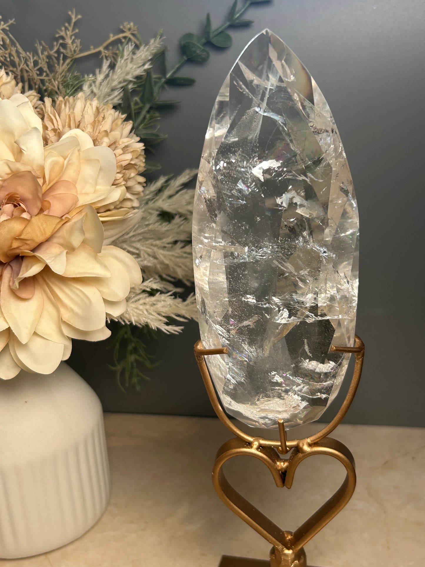 Faceted clear quartz crystal display piece on gold stand with geometric cut natural quartz specimen.