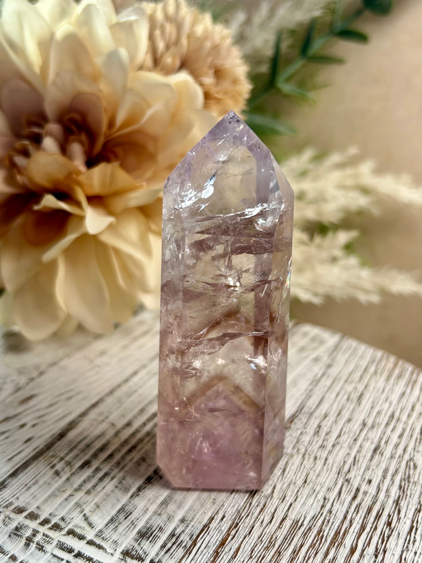 Crystal tower on a wooden surface with flowers in the background