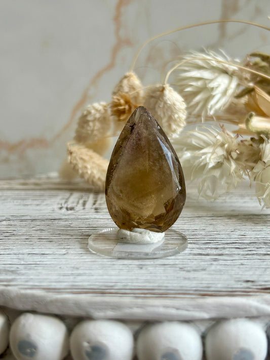 Faceted natural Citrine freeform with soft golden colour and visible internal inclusions, displayed against a neutral background.