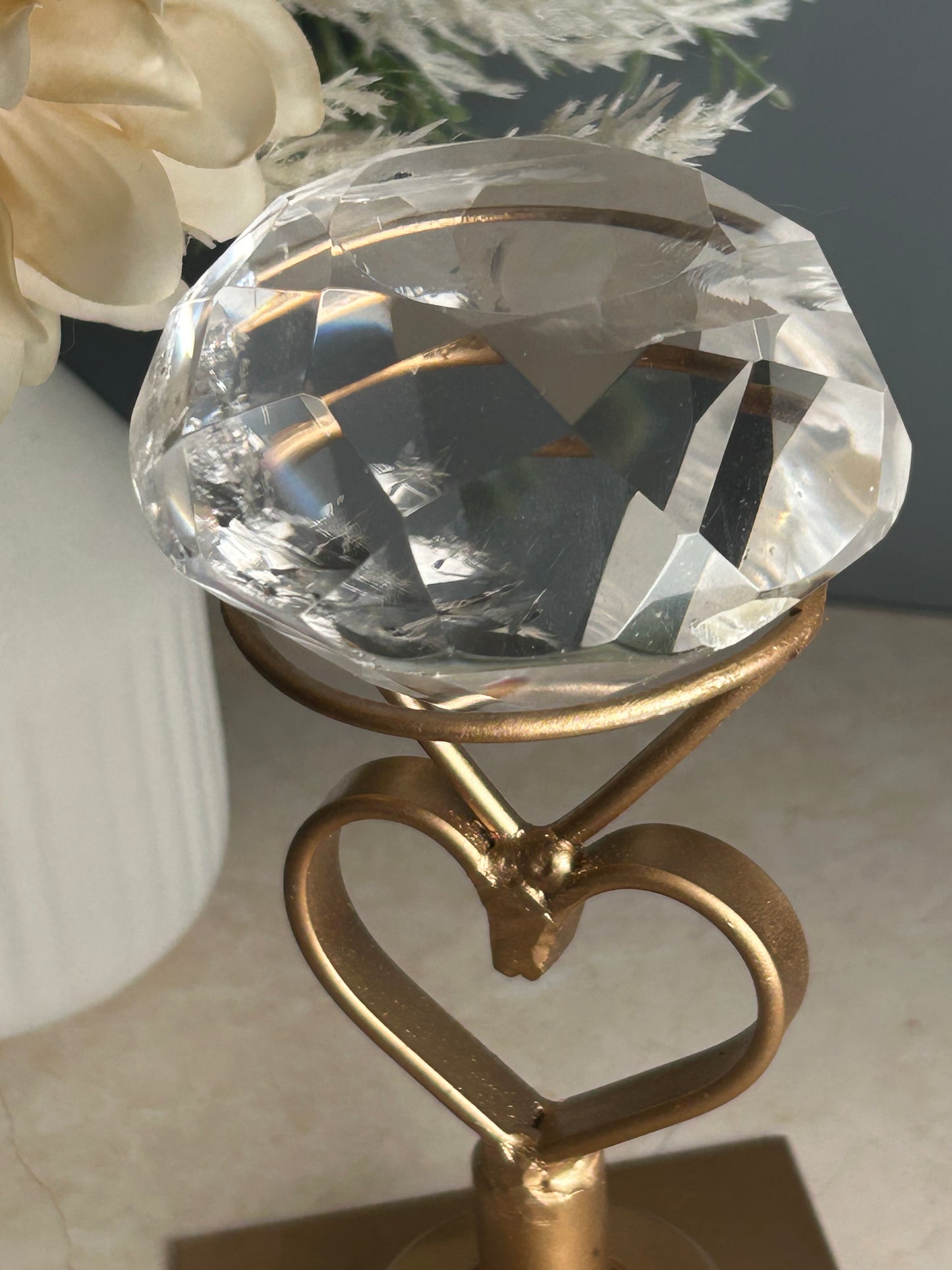Faceted clear quartz crystal display piece on gold stand with geometric cut natural quartz specimen.
