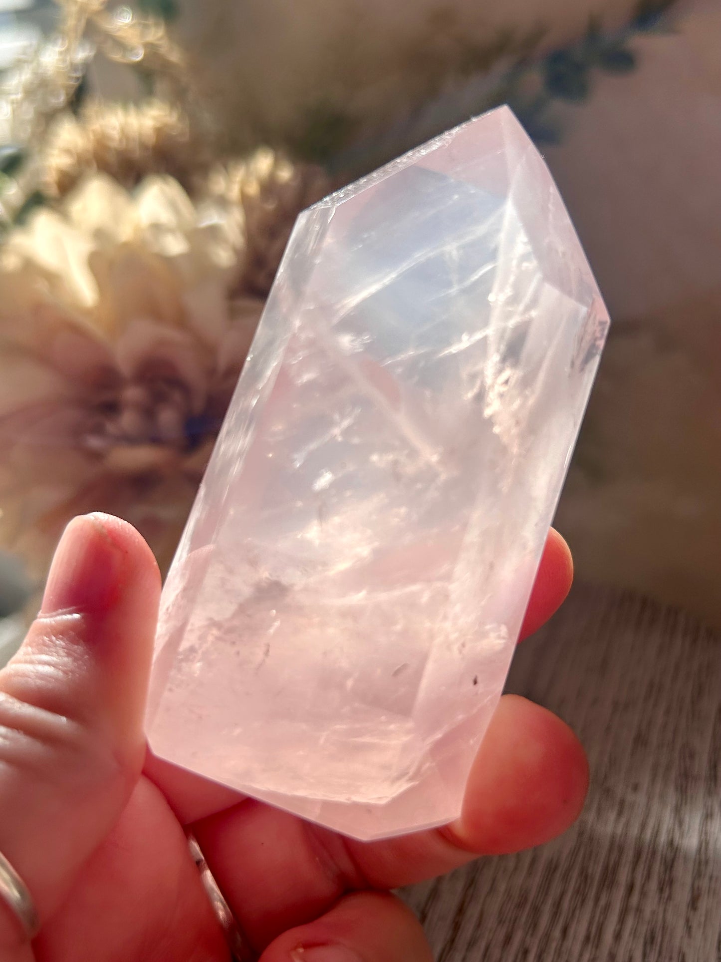 Clear crystal held in a hand with a blurred natural background