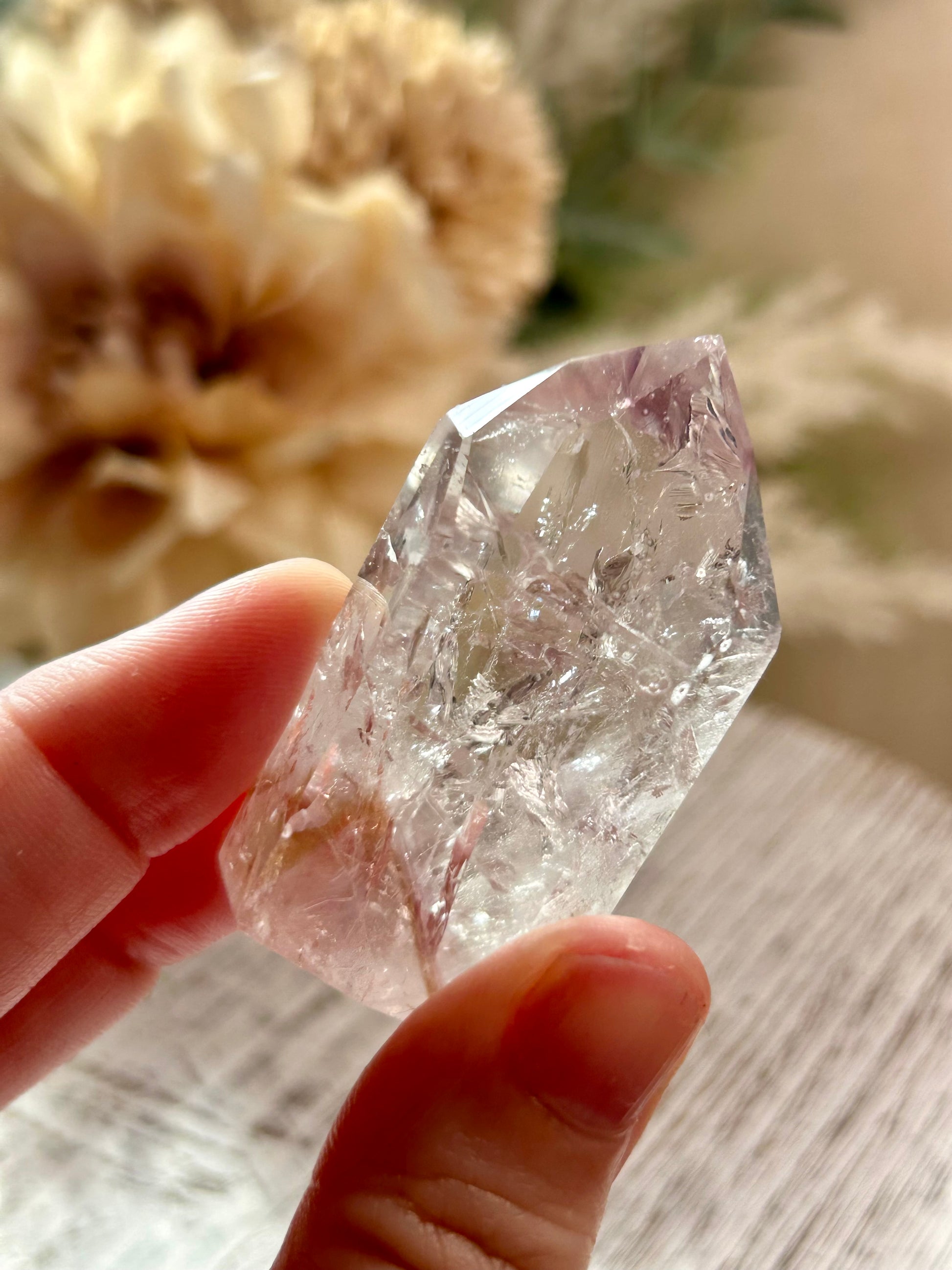Clear crystal held in a hand with a blurred natural background