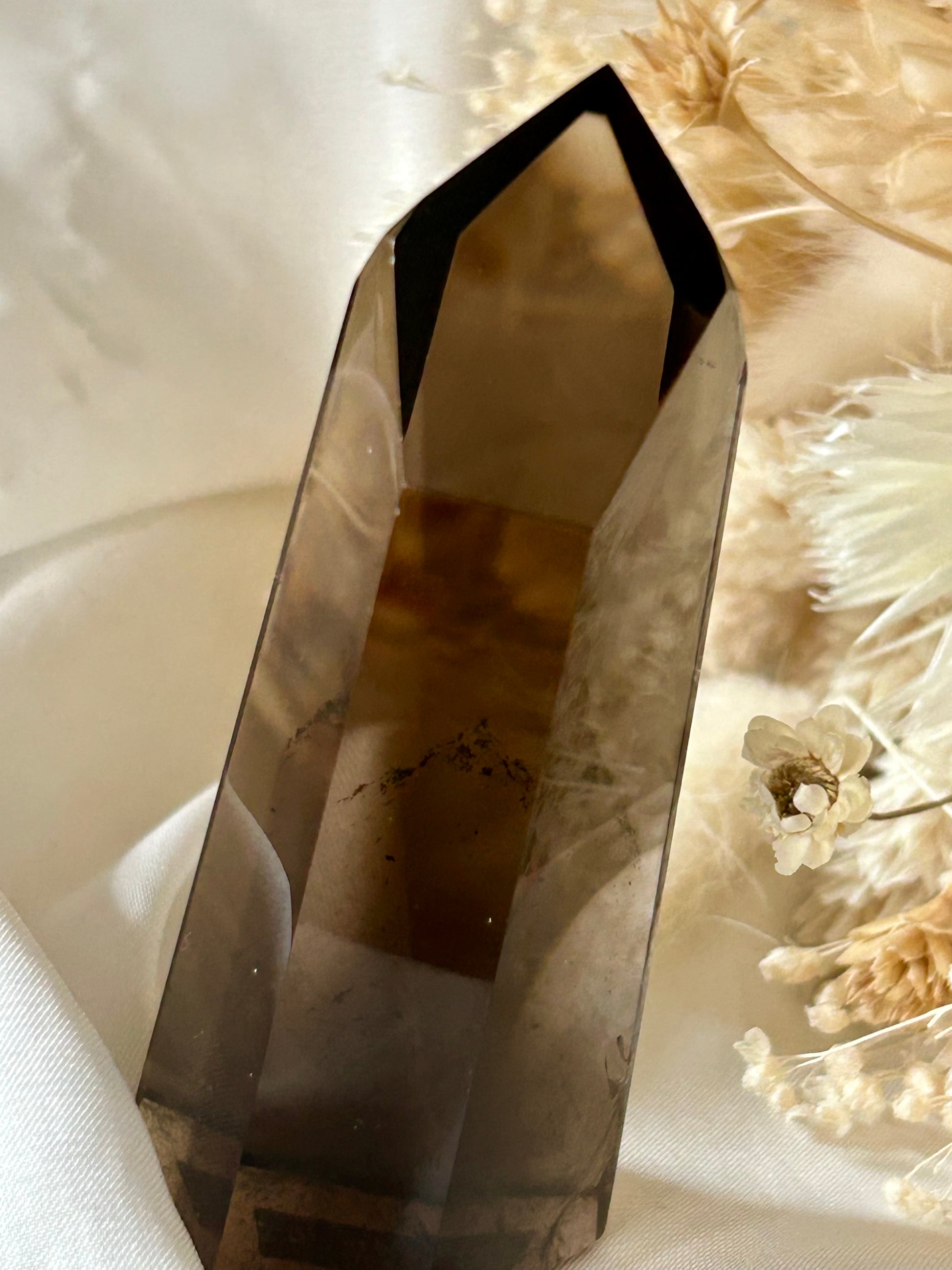 Smokey Quartz crystal with warm brown tones and soft clarity, standing upright on neutral background