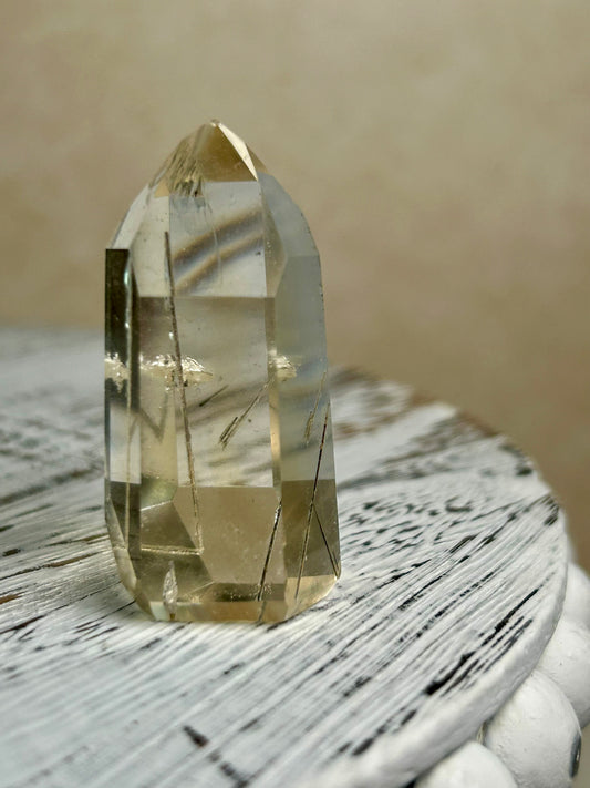 Citrine Rutile tower with golden threads on cream background and rustic wood surface