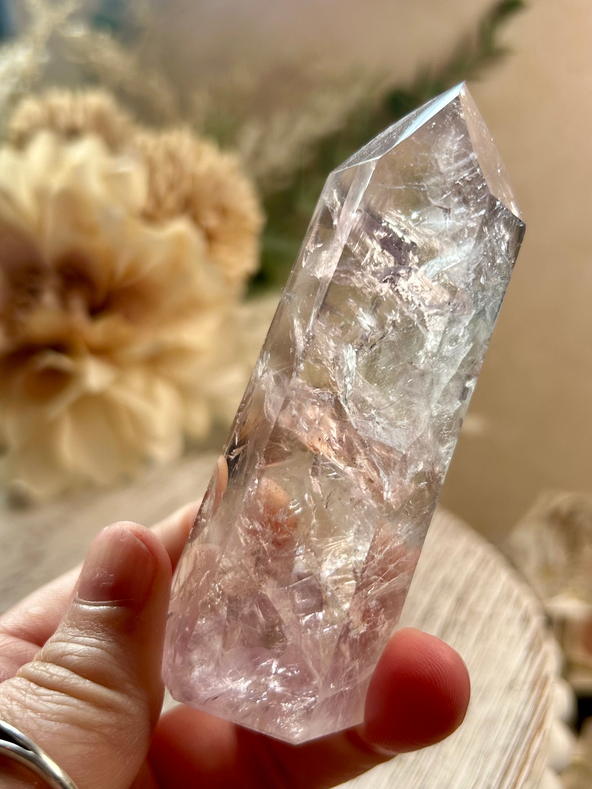Clear crystal held in a hand with a blurred natural background