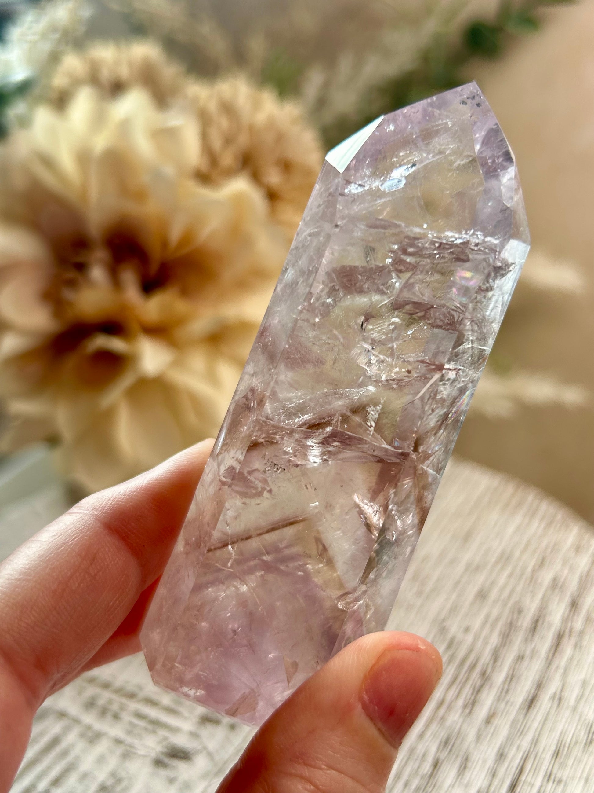 Clear crystal held by a hand with a blurred natural background