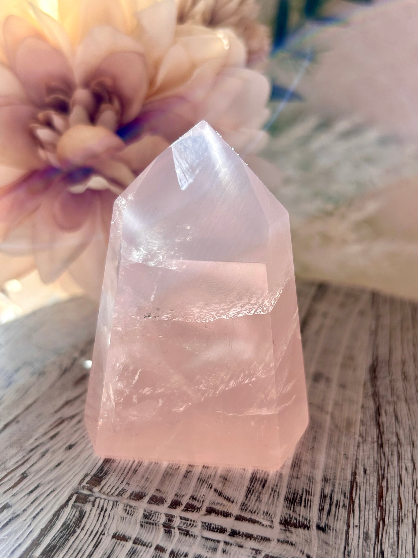 Crystal tower on a wooden surface with flowers in the background