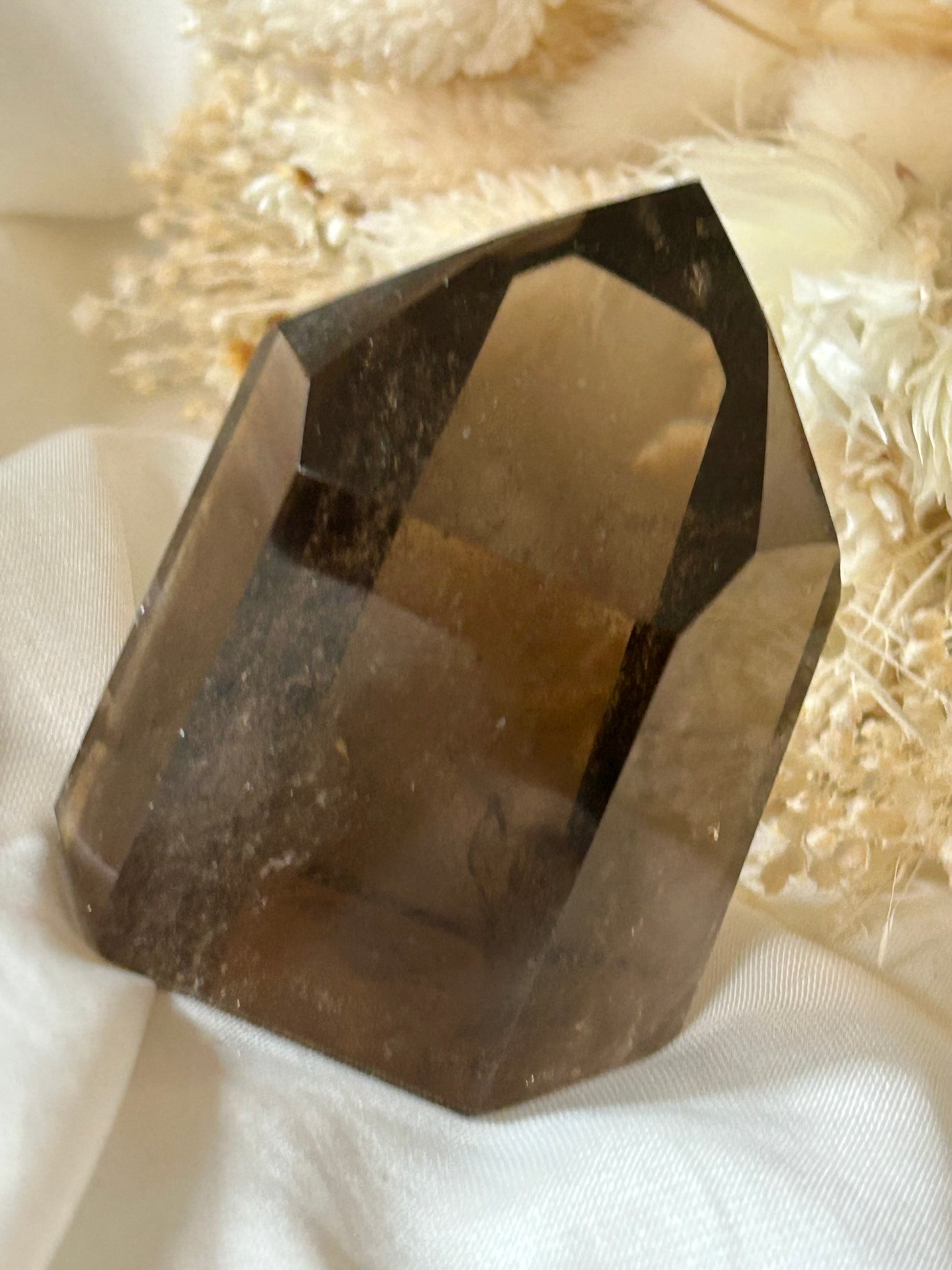 Smokey Quartz crystal with warm brown tones and soft clarity, standing upright on neutral background