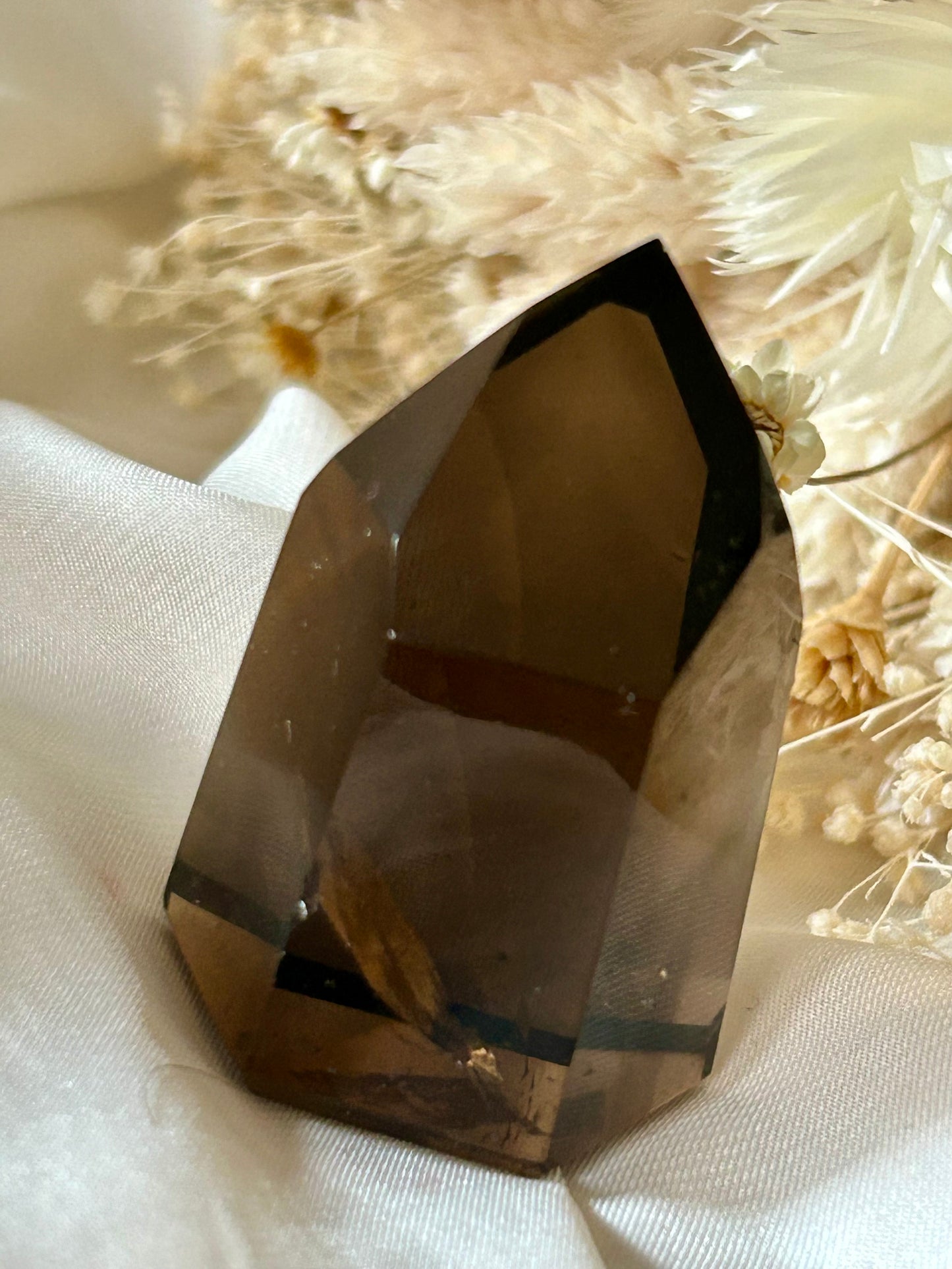 Smokey Quartz crystal with warm brown tones and soft clarity, standing upright on neutral background
