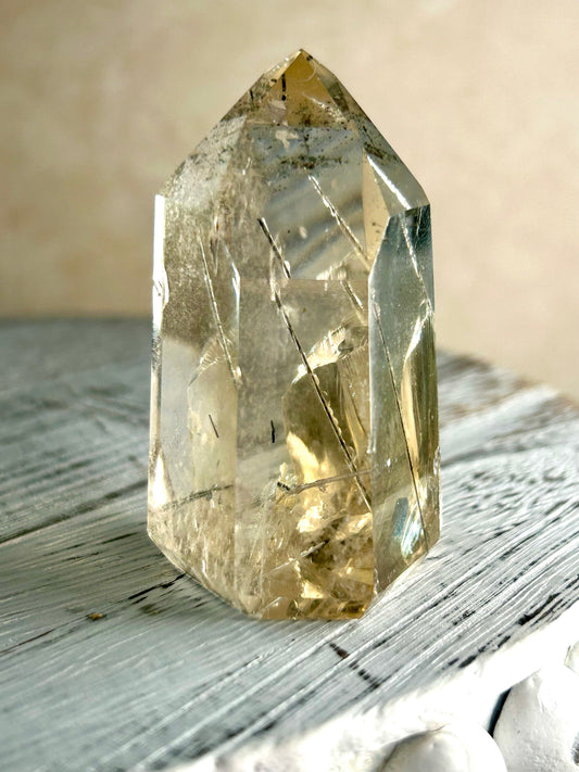 Citrine Rutile tower with golden threads on cream background and rustic wood surface