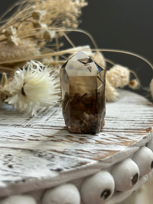 High grade lodolite rutile quartz crystal with layered internal inclusions, photographed in soft natural light.
