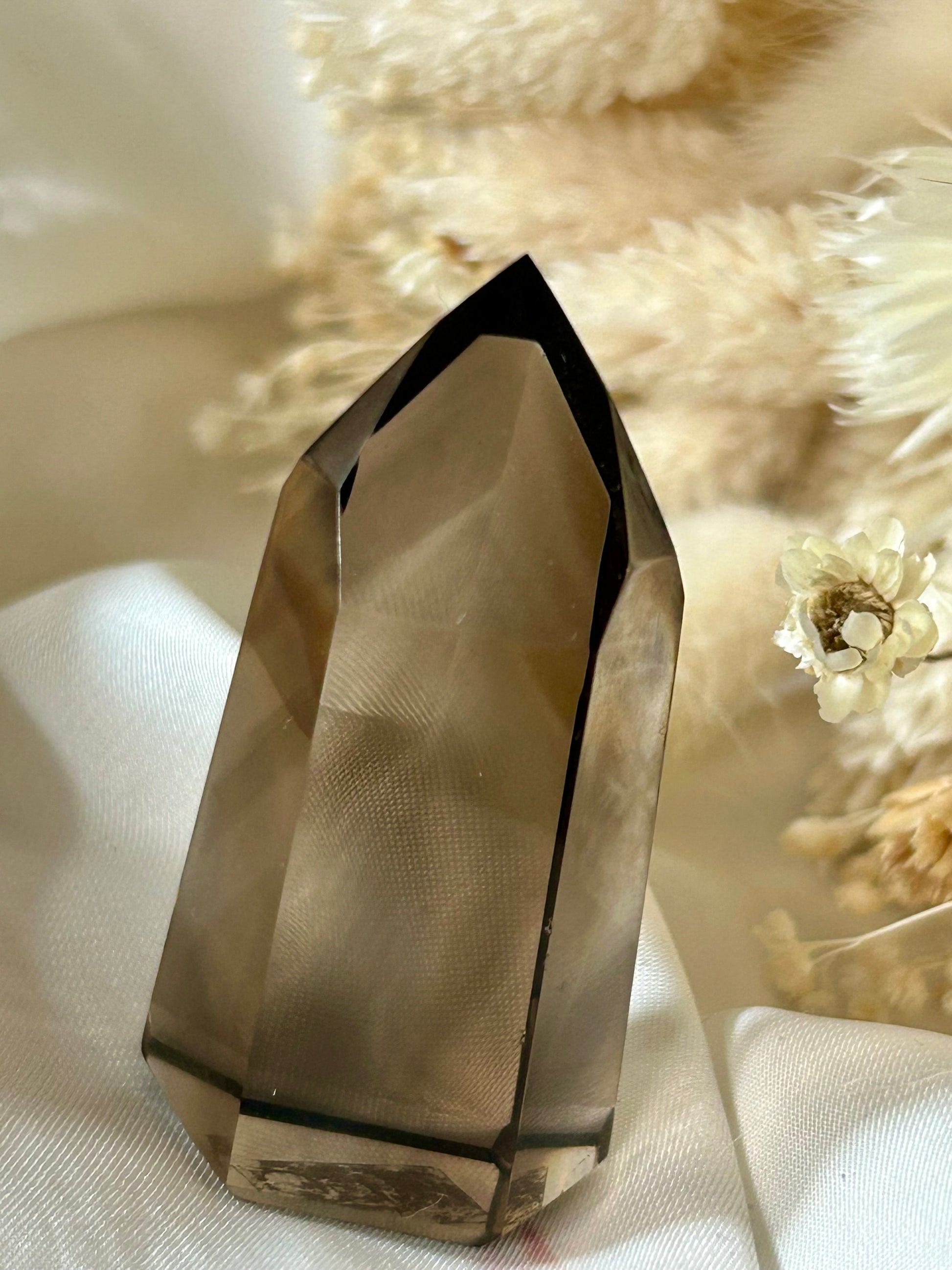 Smokey Quartz crystal with warm brown tones and soft clarity, standing upright on neutral background