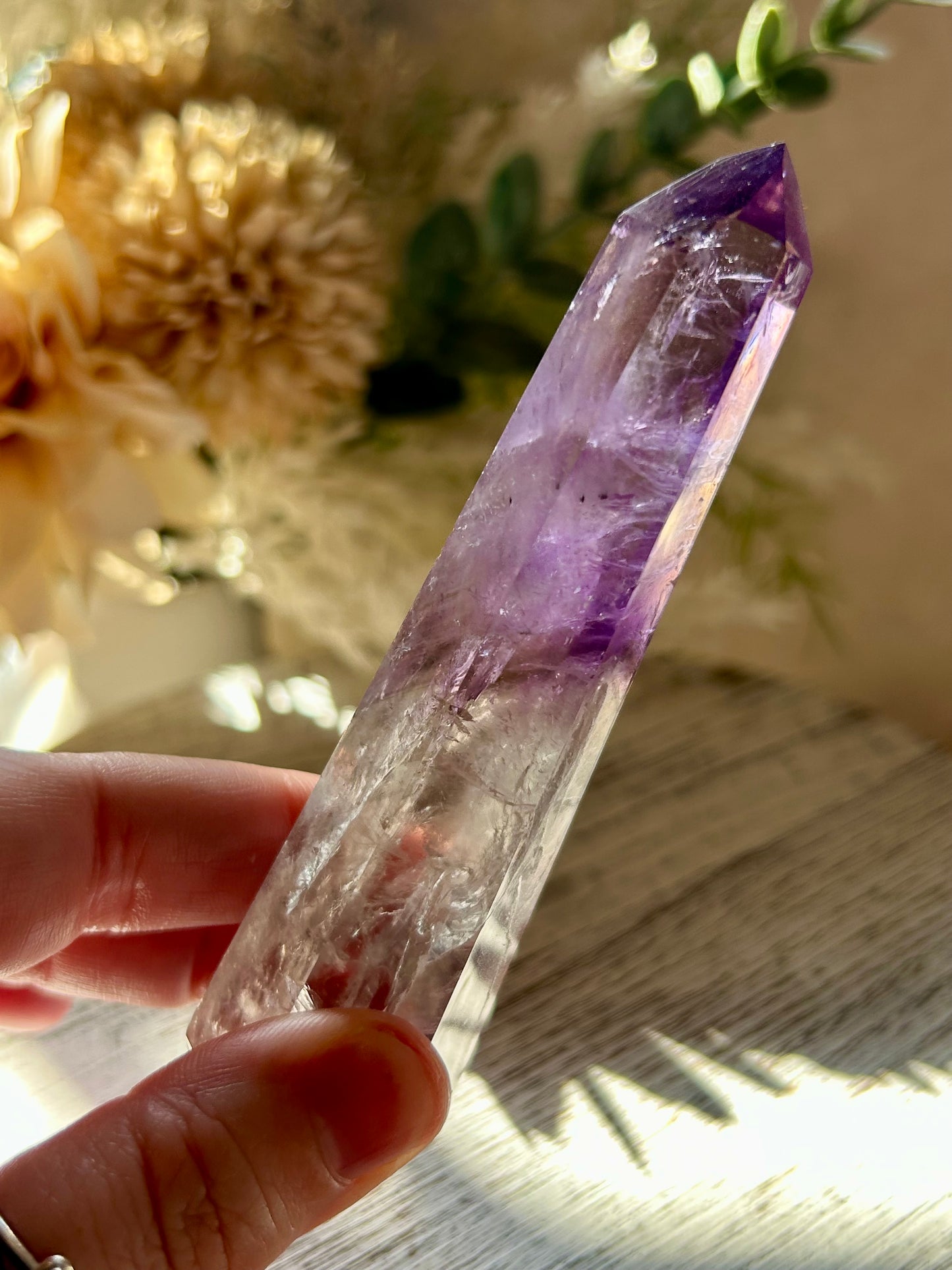 Amethyst crystal held by a hand with a blurred natural background
