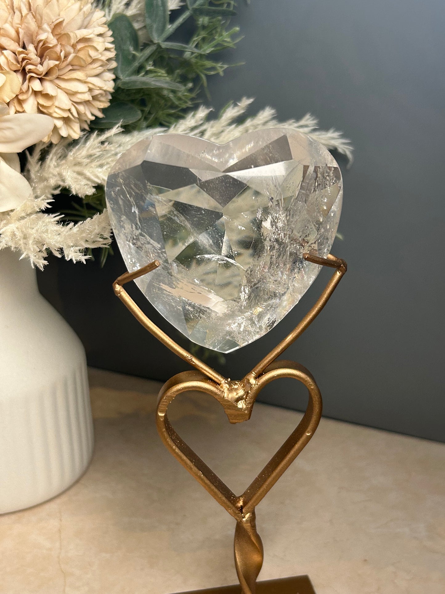 Faceted clear quartz crystal display piece on gold stand with geometric cut natural quartz specimen.
