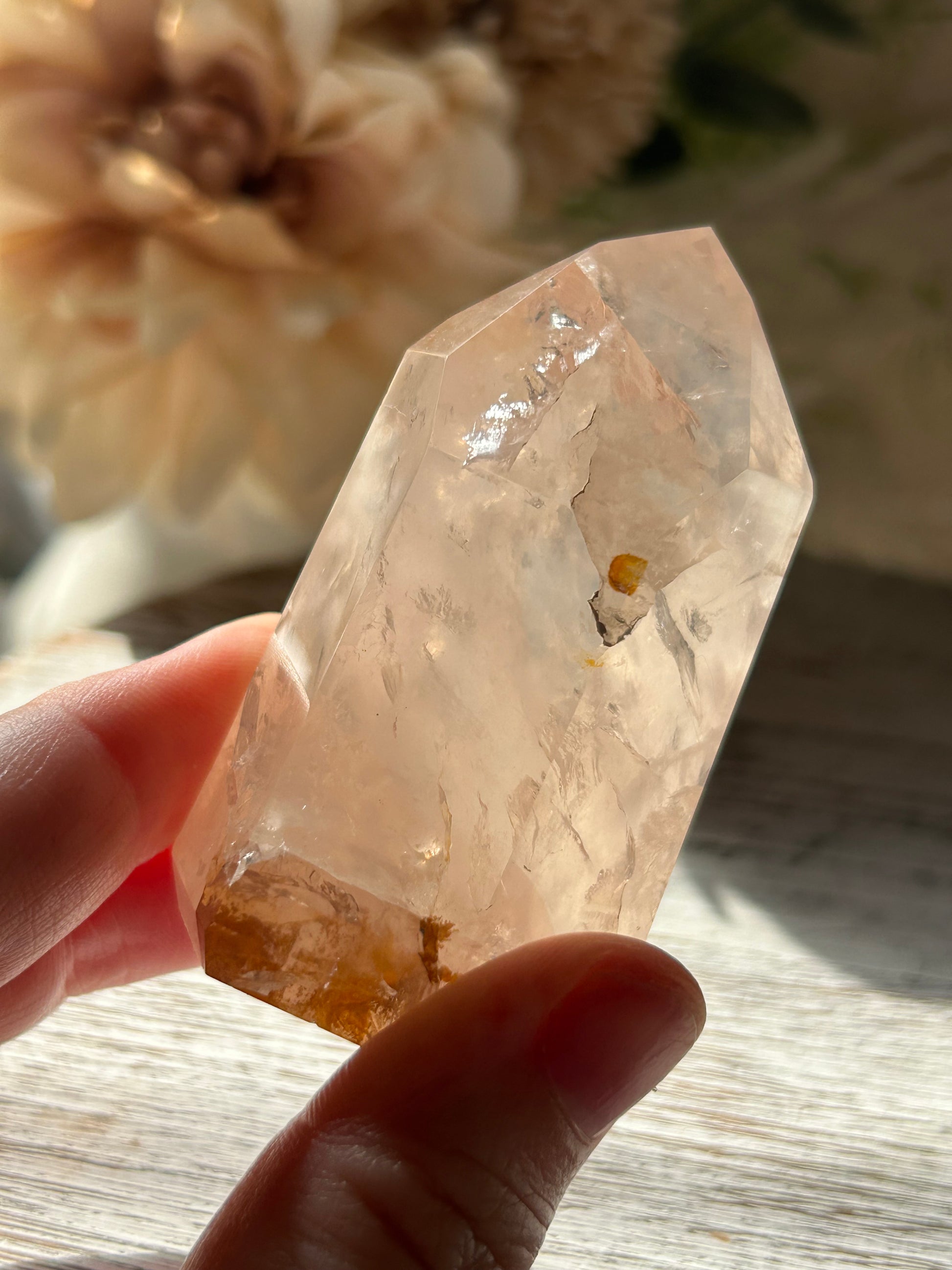 Clear crystal held by a hand with a blurred natural background