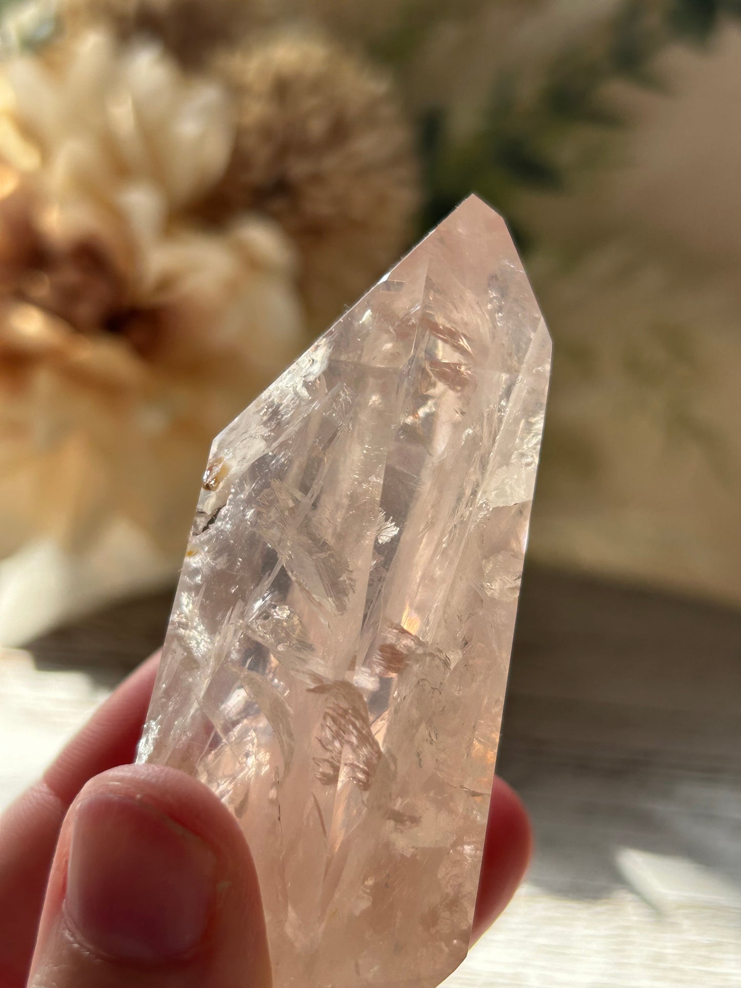 Clear crystal held by a hand with a blurred natural background