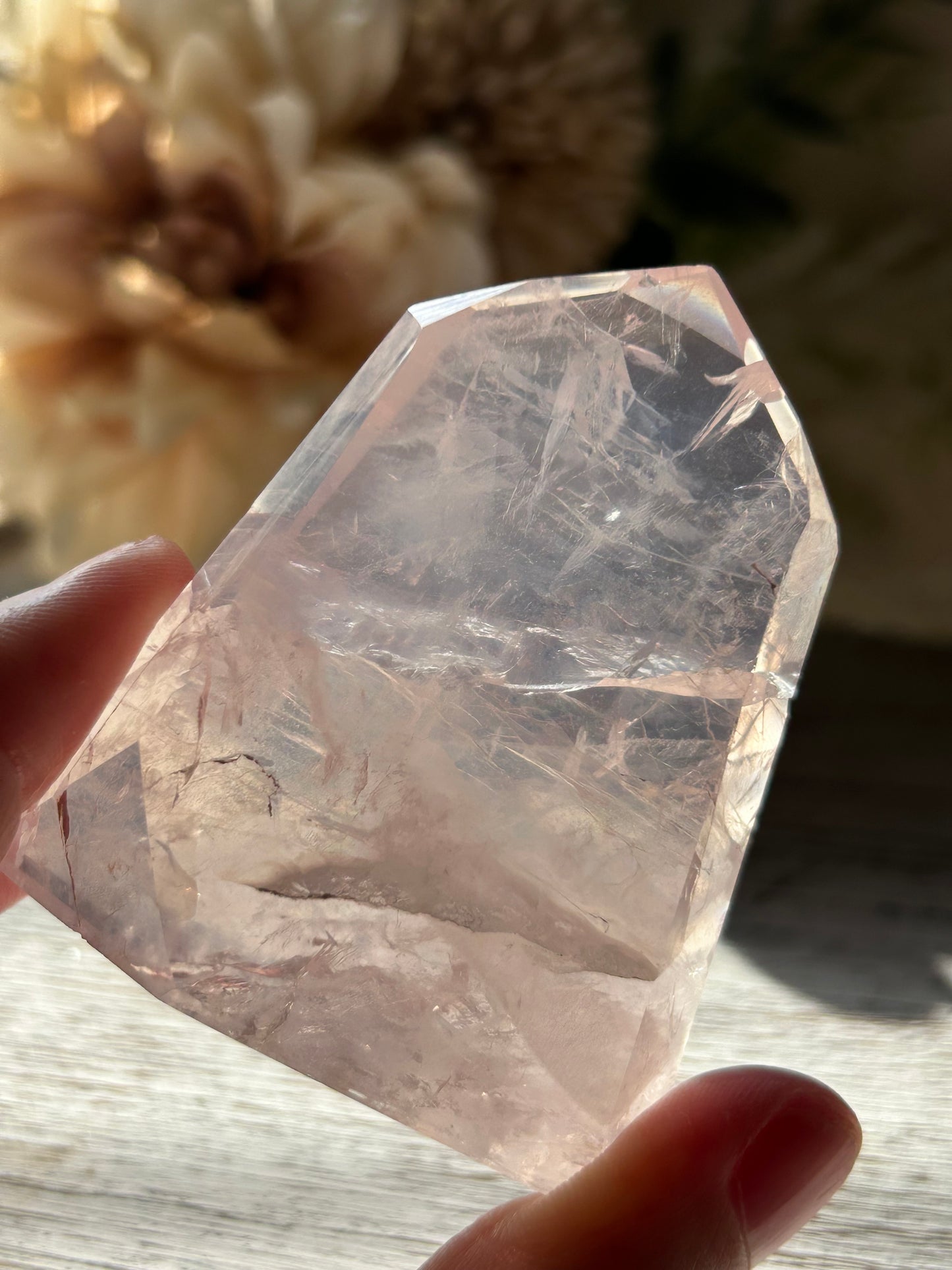 Clear crystal held by a hand with a blurred background