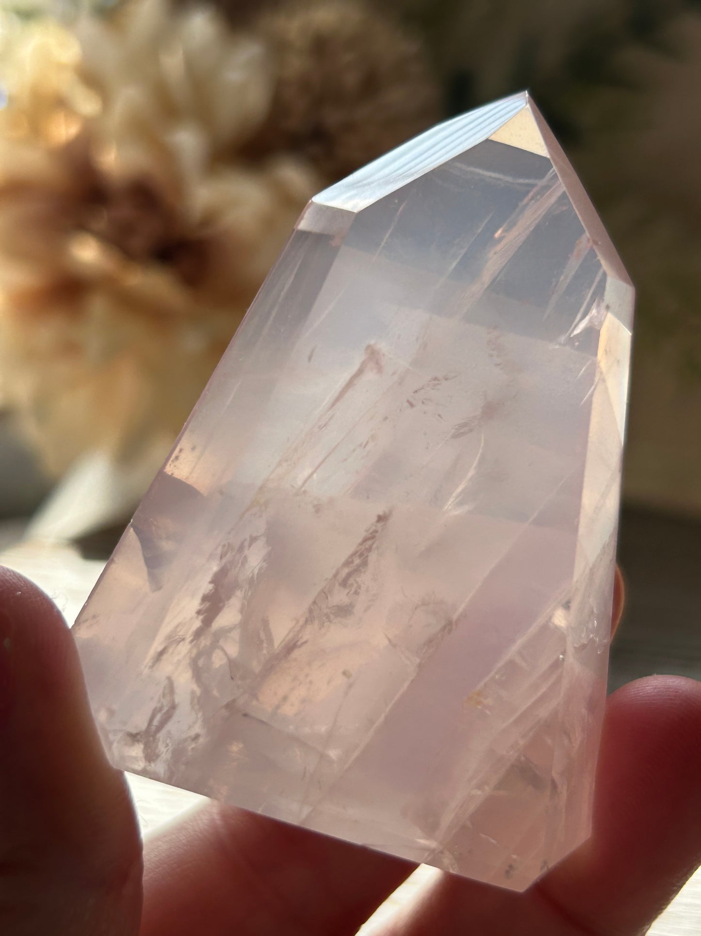 Clear crystal held by a hand with a blurred background