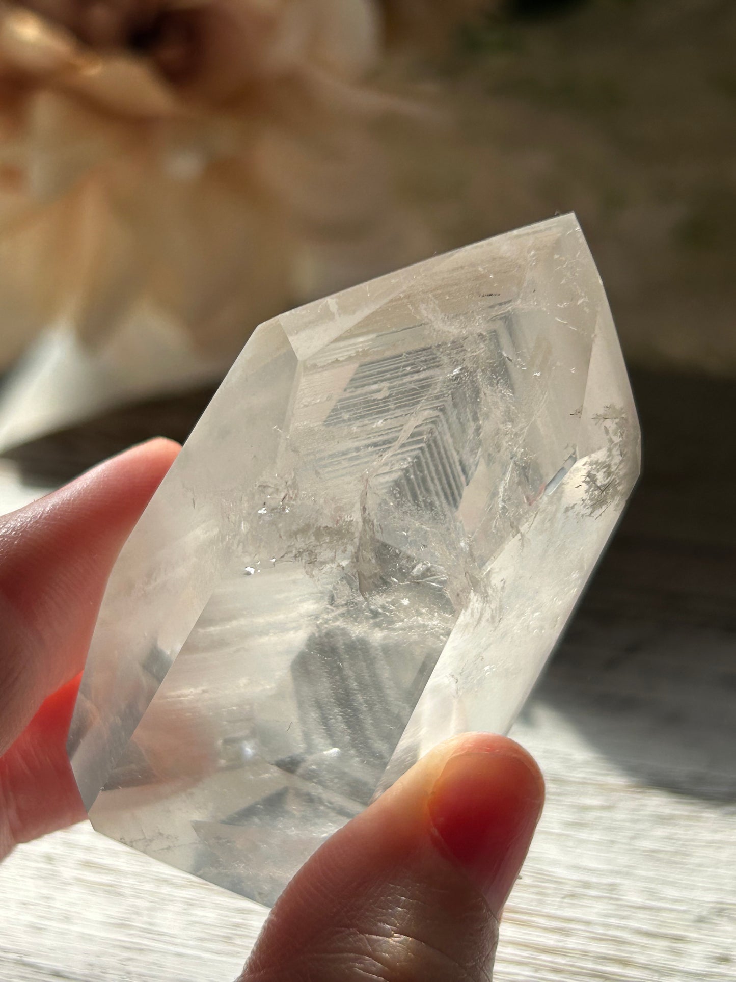 Clear crystal held by a hand with a blurred background