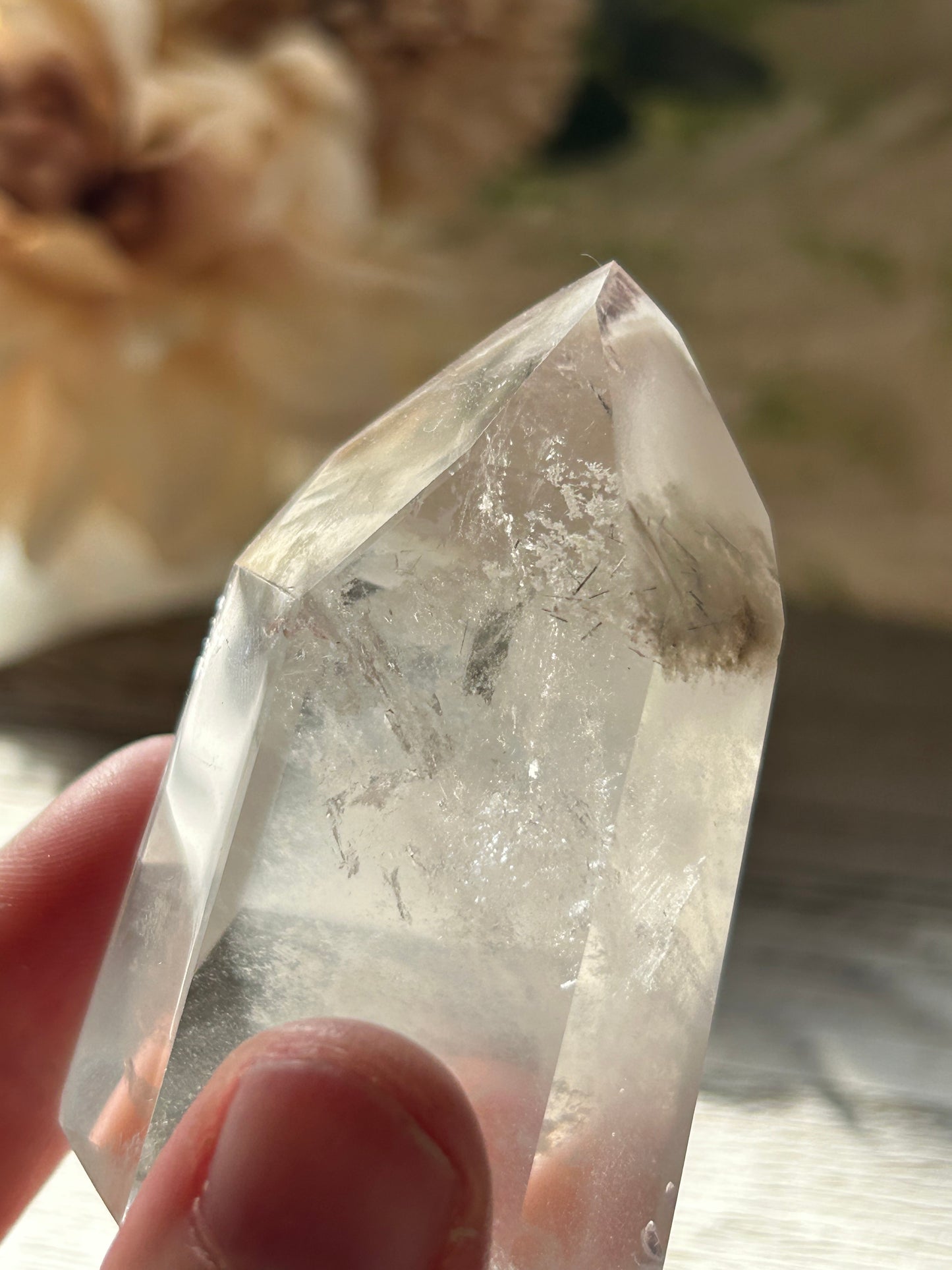 Clear crystal held by a hand with a blurred natural background