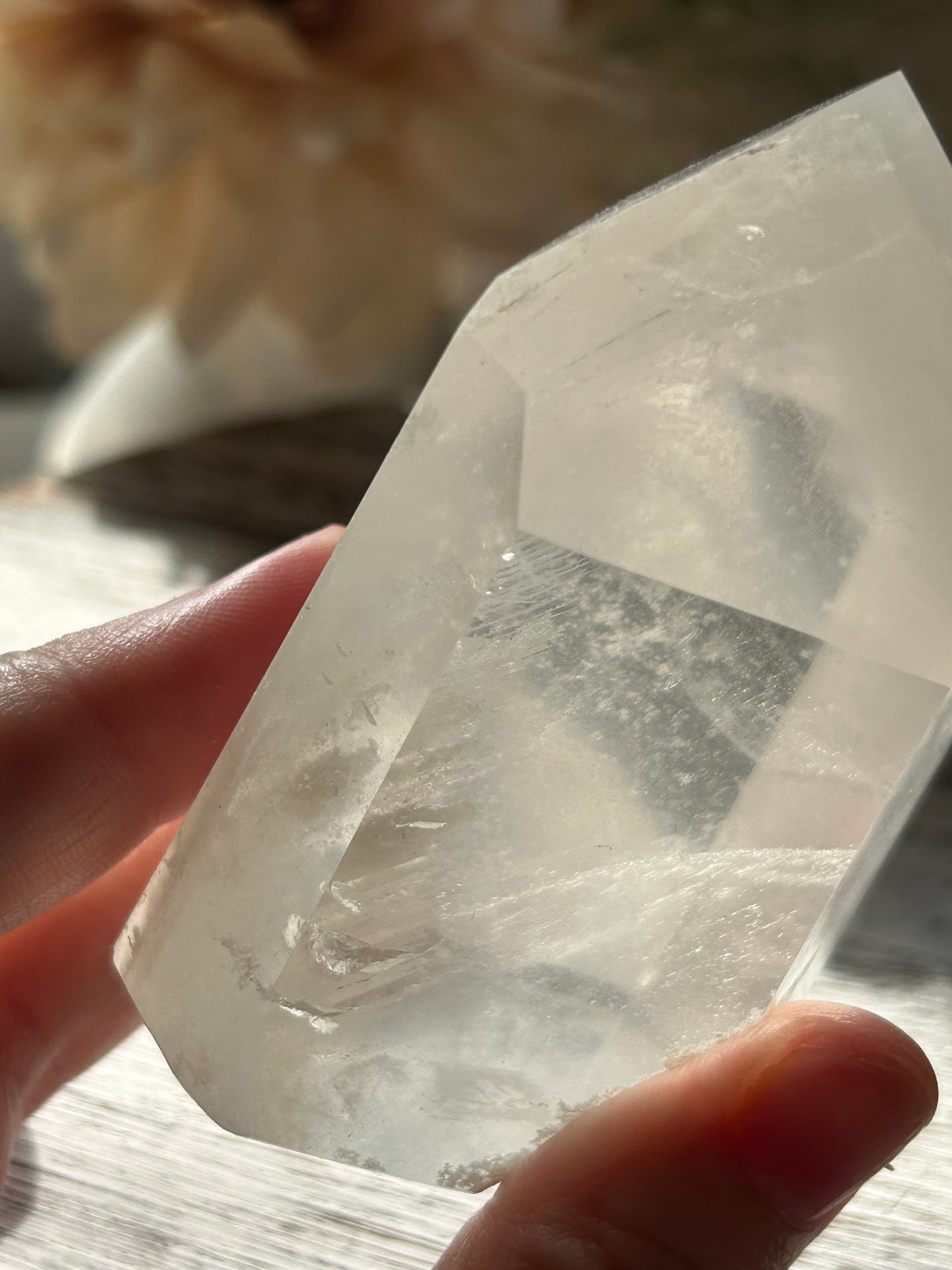 Clear crystal held by a hand with a blurred background
