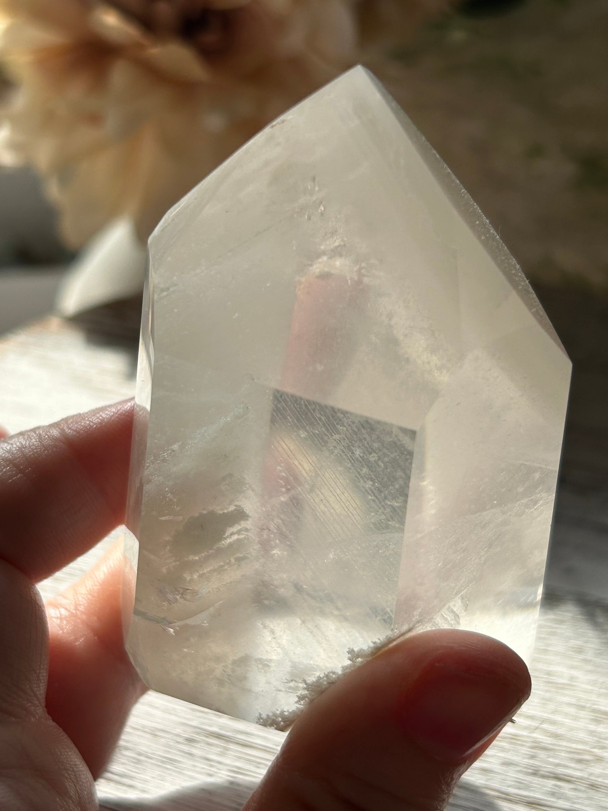 Person holding a clear crystal with a hexagonal shape