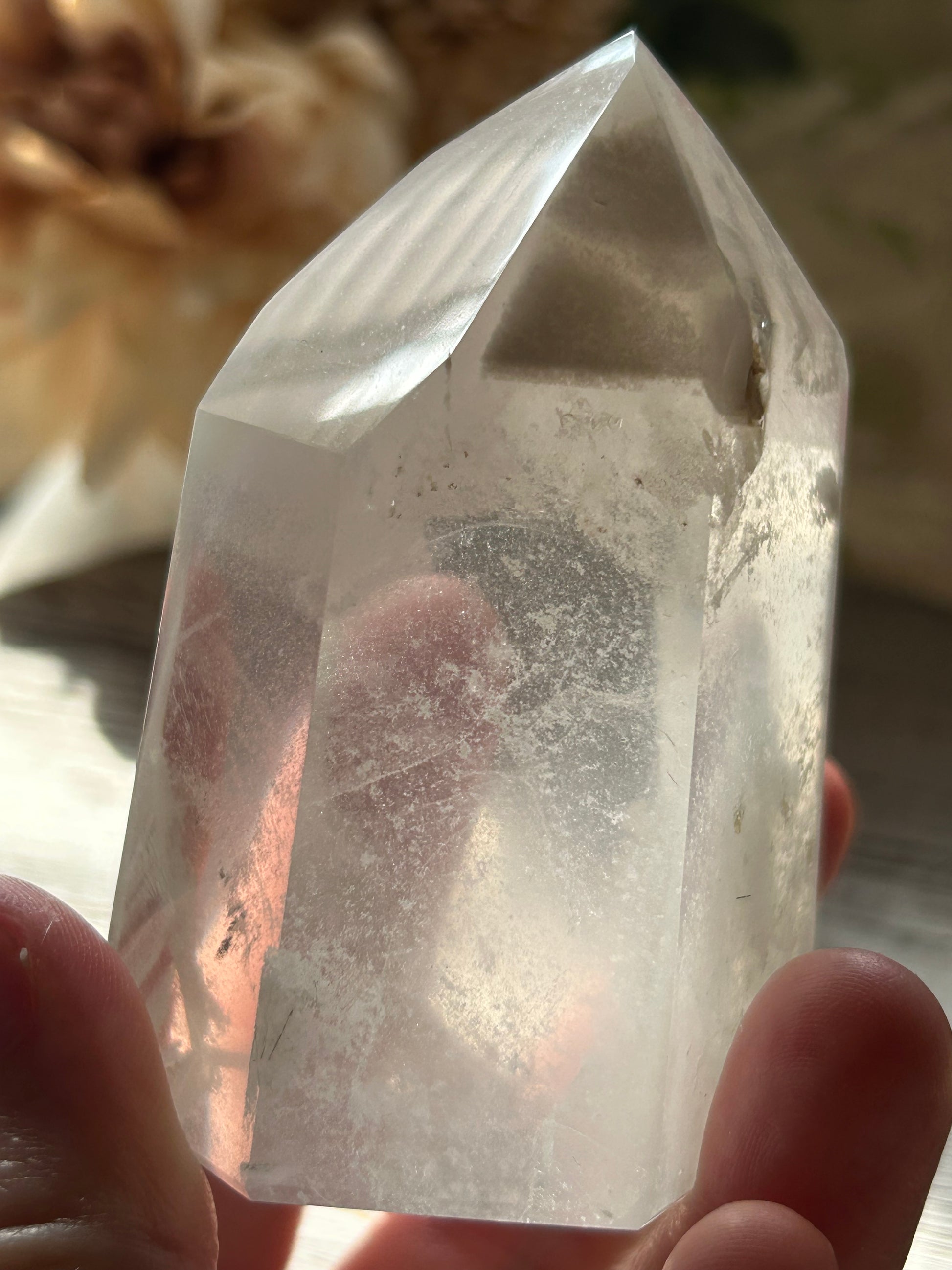 Clear crystal held in a hand with a blurred background