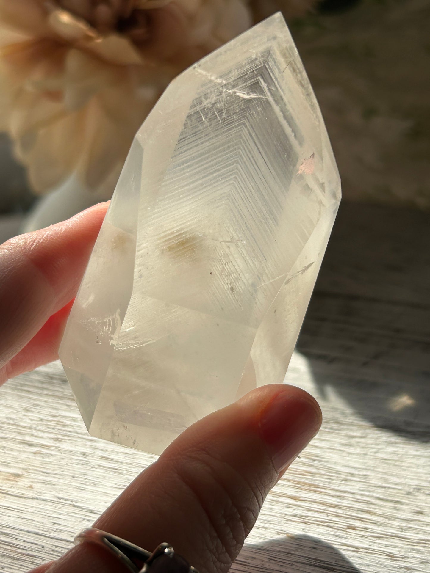 Clear crystal held by a hand on a wooden surface