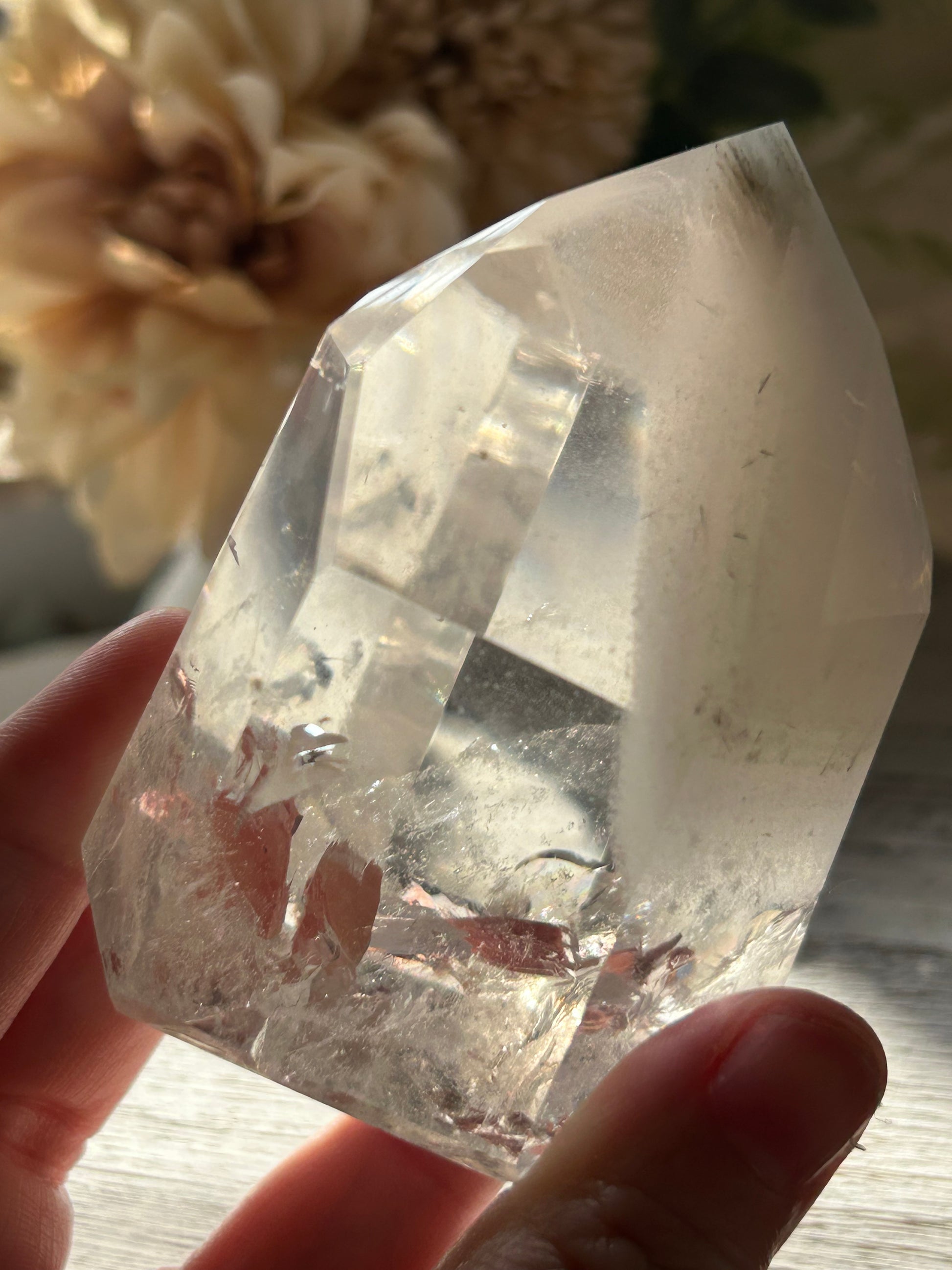 Clear crystal held by a hand with a blurred background