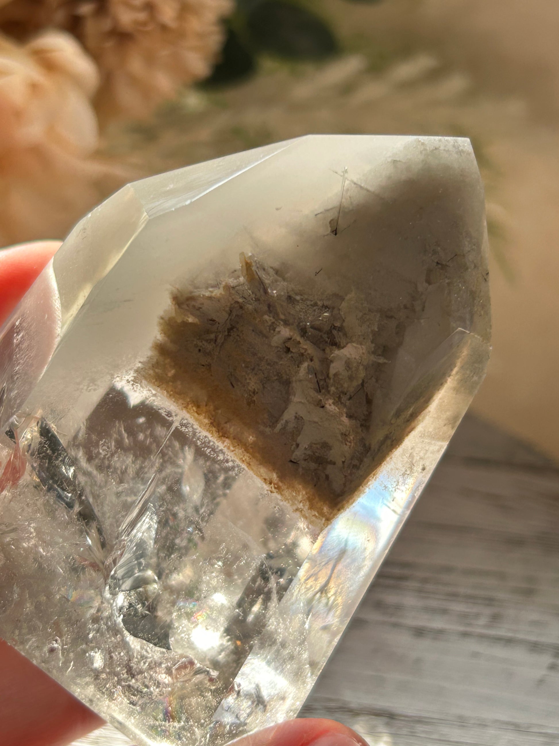 Clear crystal held by a hand with a blurred background