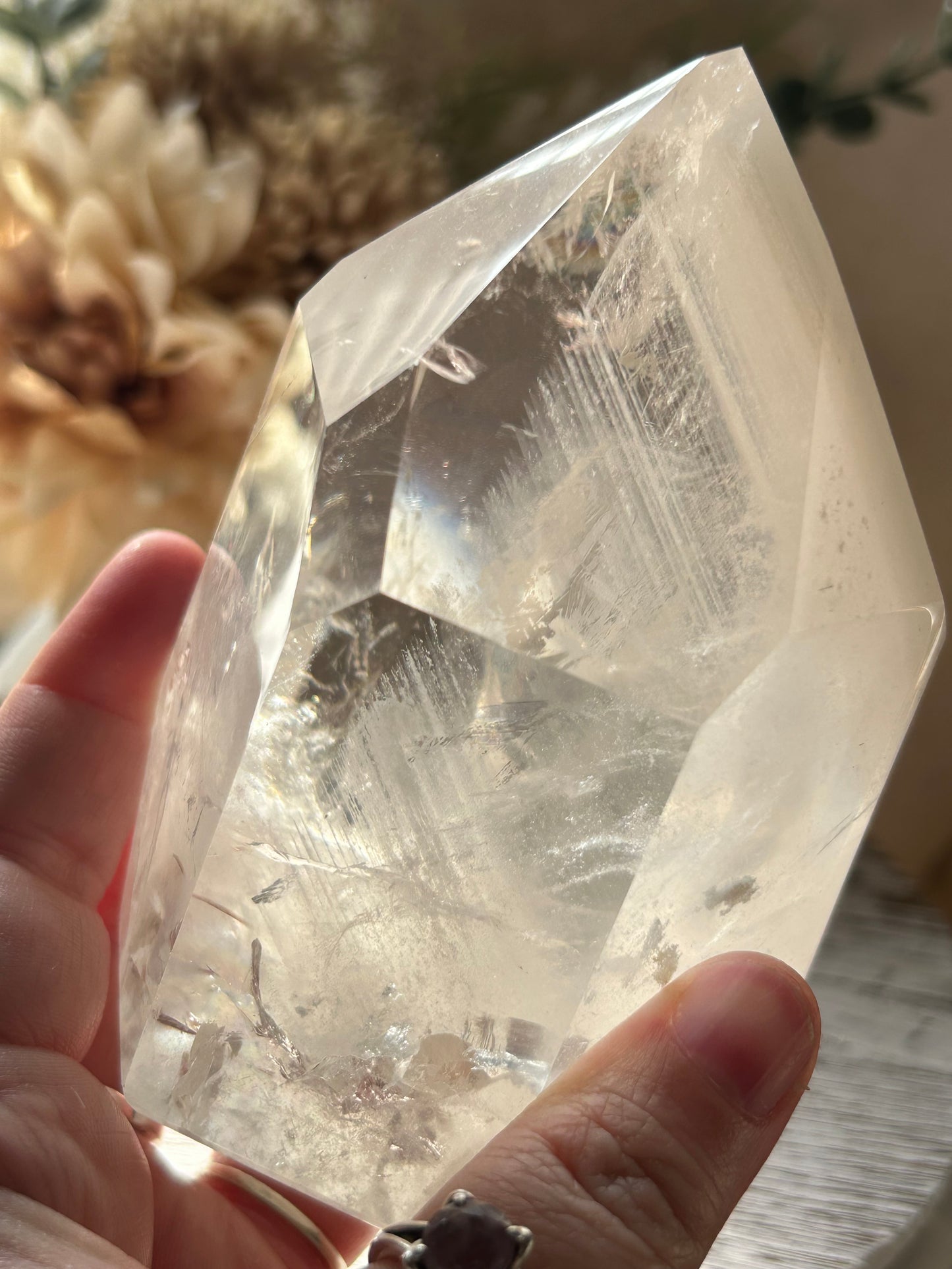Clear crystal held by a hand with a blurred natural background